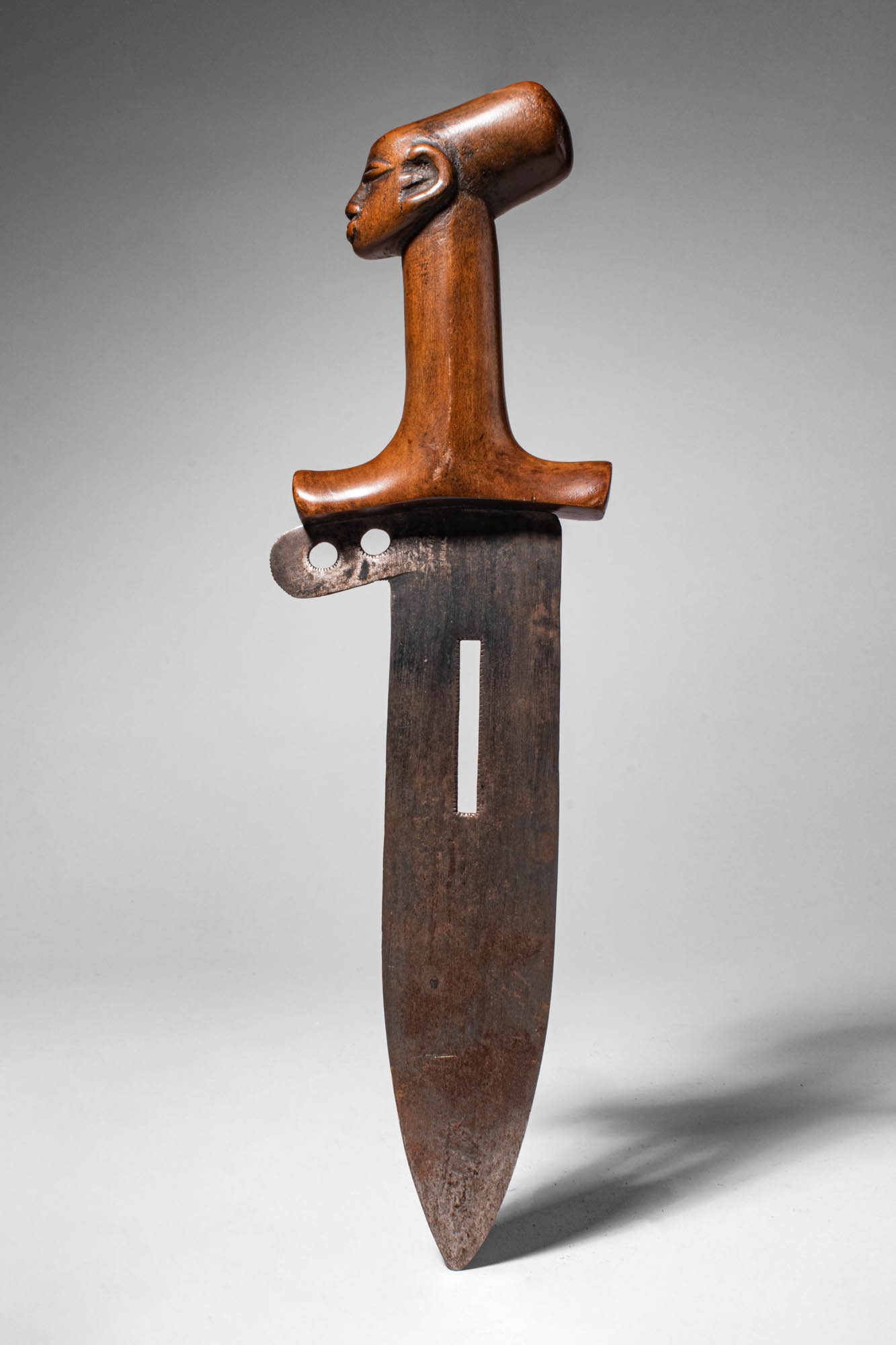 MANGBETU ANTHROPOMORPHIC NAMAMBELE KNIFE: Ca. 19th - 20th century AD. >An iron knife set in a wooden handle with a sculptural pommel in the shape of a woman's head. Knives of this design were worn on the hip and were considered a mark of