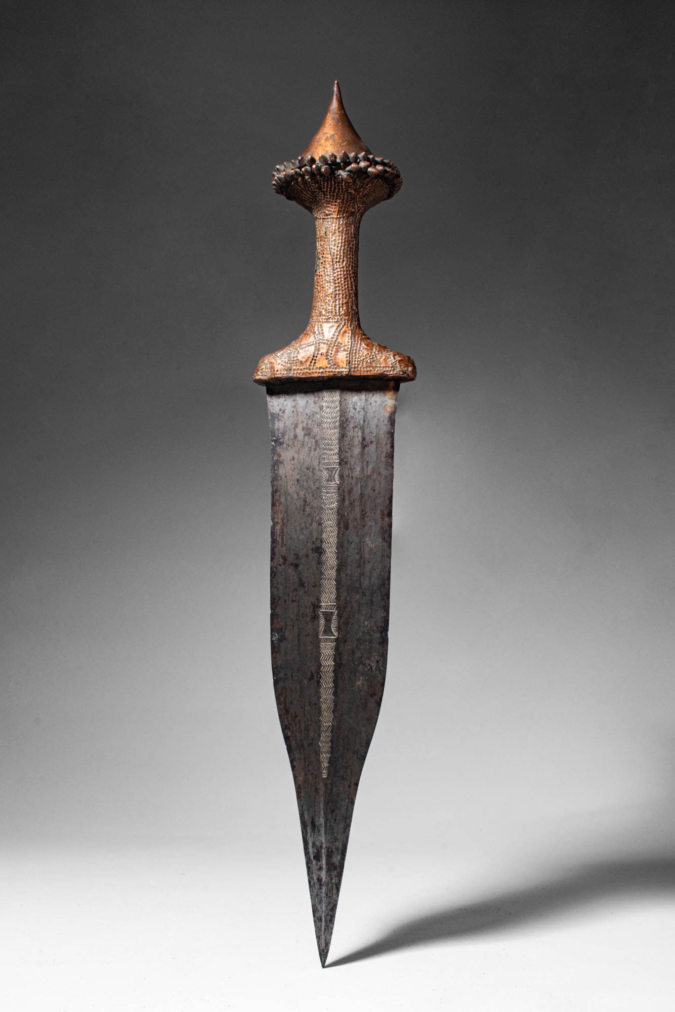 TETELA KNIFE WITH COPPER HANDLE: Ca. 19th - 20th century AD. >A knife with a handle made from wood which has been covered by a thin plate of hammered decorated bronze. The handle of this weapon may have been made by the Tetela