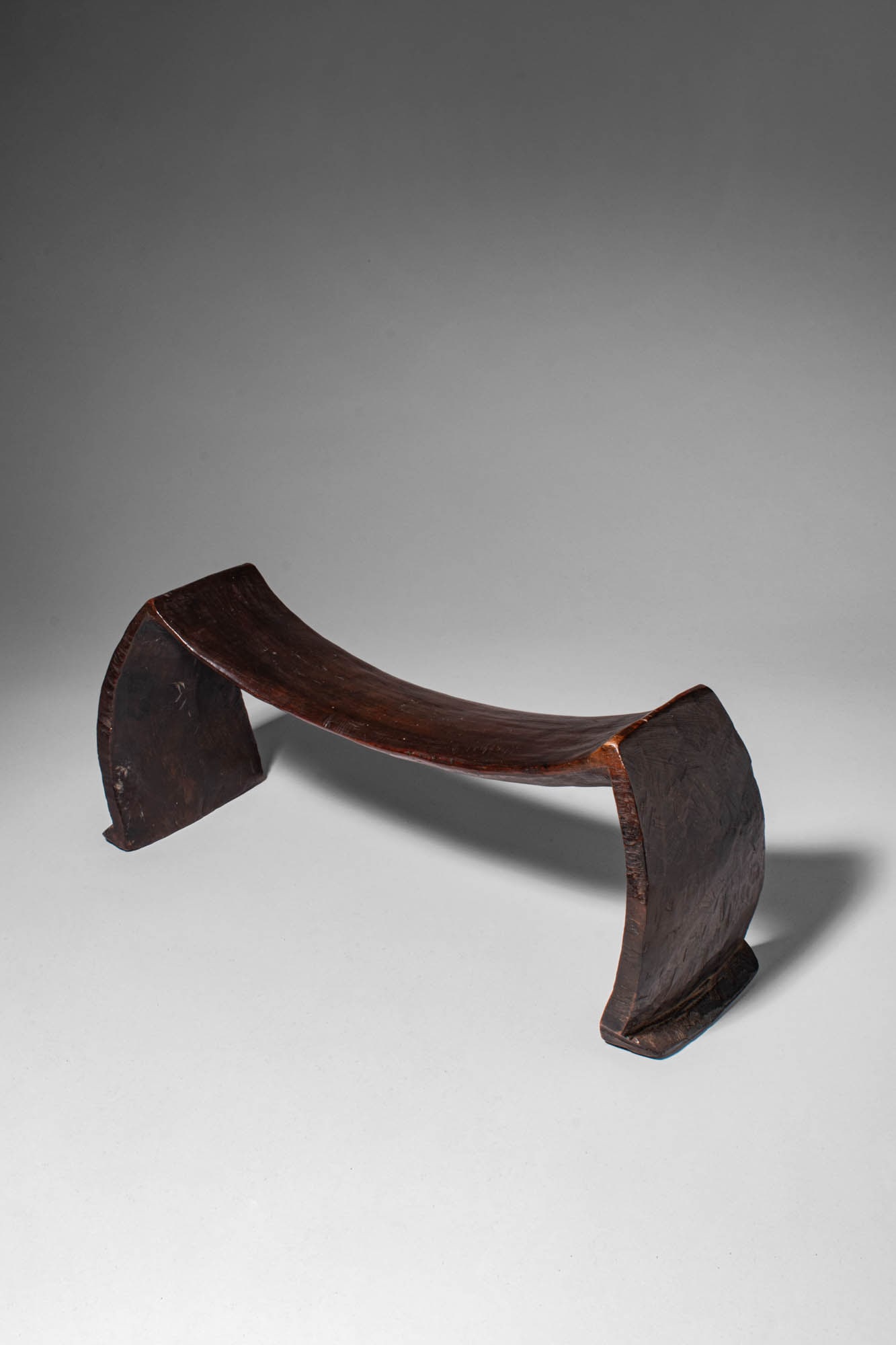 TONGAN KALI HEADREST: Ca. late 19th - early 20th century AD. >A beautiful Tongan headrest carved with a gently concave upper support raised on two flared, angular legs. The resting bar has a subtle inward curve, shaped to