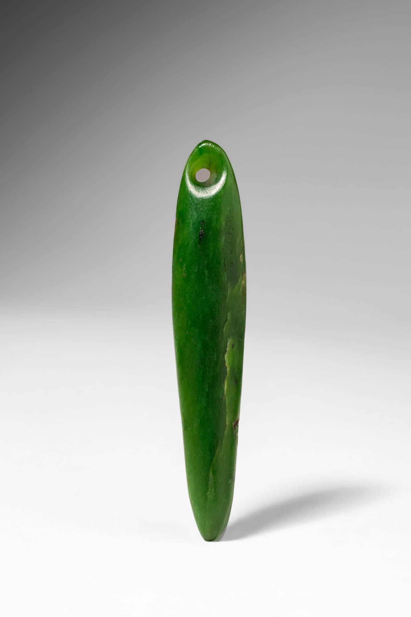 MAORI KURUKURU JADE PENDANT: Ca. 19th century AD or earlier. >A Kurukuru jade pendant of elongated, gently tapering form, carved from richly coloured green nephrite and carefully polished to a soft lustre. A circular suspension