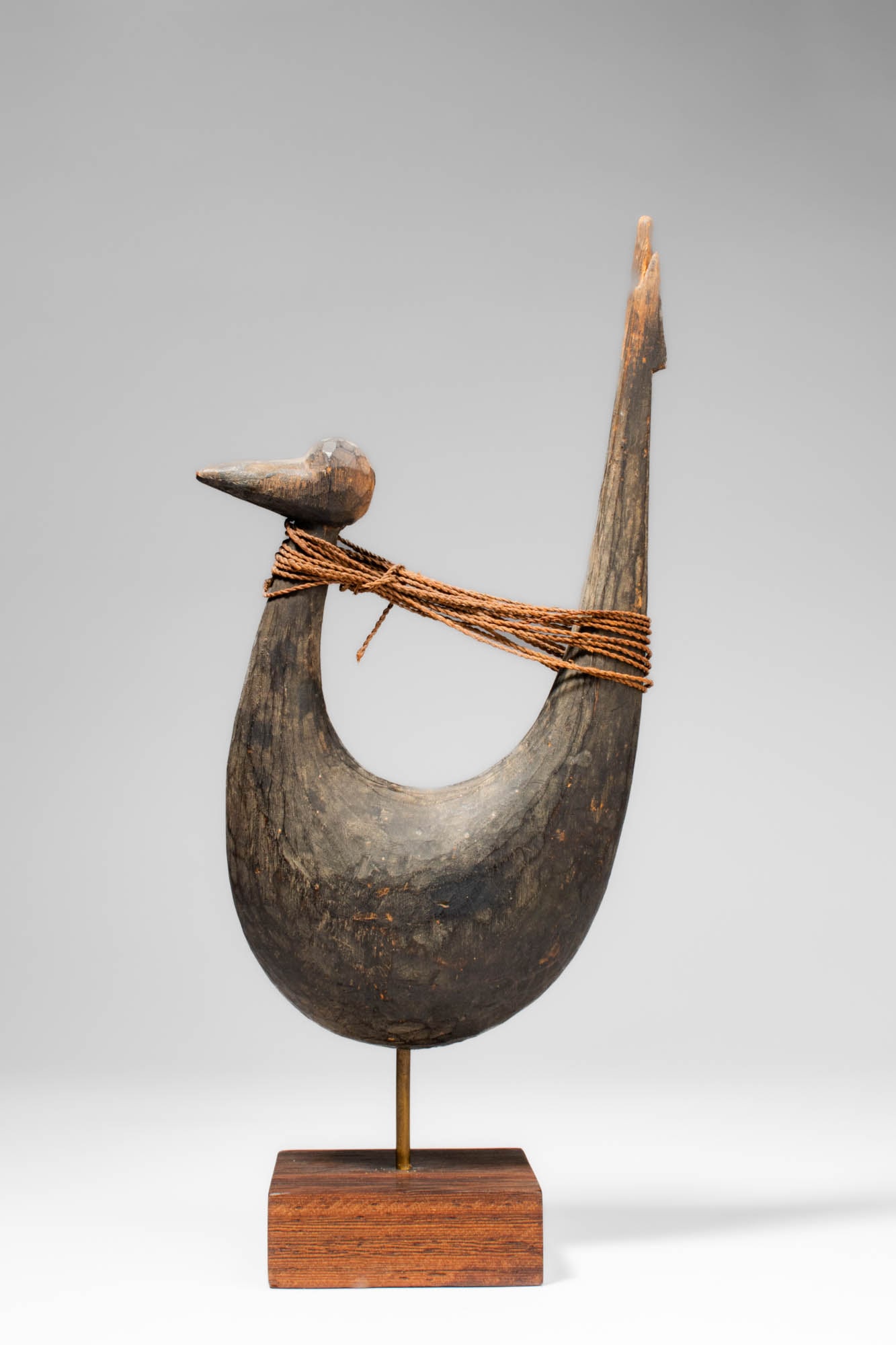 OCEANIC WOODEN IMPLEMENT: Ca. 20th century AD. >A wooden fishing implement carved from a single piece of wood. The implement is formed with a curved hook-shaped body terminating in two projecting ends. One end is carved in the