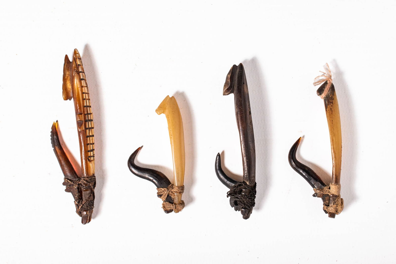 GROUP OF SOLOMON ISLANDS FISH HOOKS: Ca. 19th century AD. A group of four fish hooks, each constructed from a combination of shell, turtle shell, bone, and fibre lashings. The hooks exhibit elegant curves and finely worked surfaces, with
