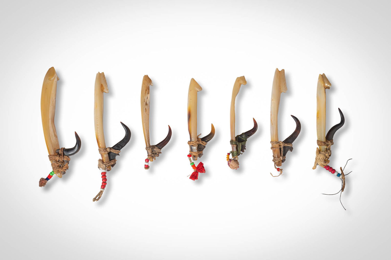 GROUP OF SOLOMON ISLANDS BONITO FISH HOOKS: Ca. 19th - 20th century AD. >A group comprising seven bonito trolling hooks, each formed with an elongated bone shank fitted with a curved shell hook secured by fibre lashings. Several examples retain