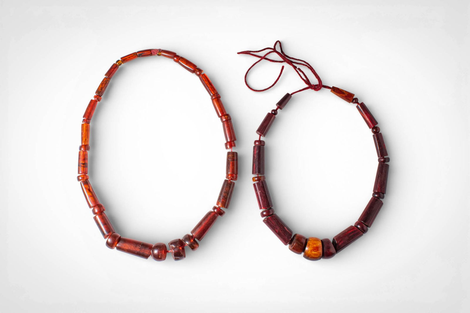 TWO INDIAN MIZORAN BRACELETS: Ca. 19th - 20th century AD. >A pair of Mizo necklaces composed of graduated cylindrical and rounded beads in warm red and amber tones. The beads are strung in rhythmic sequences, with subtle