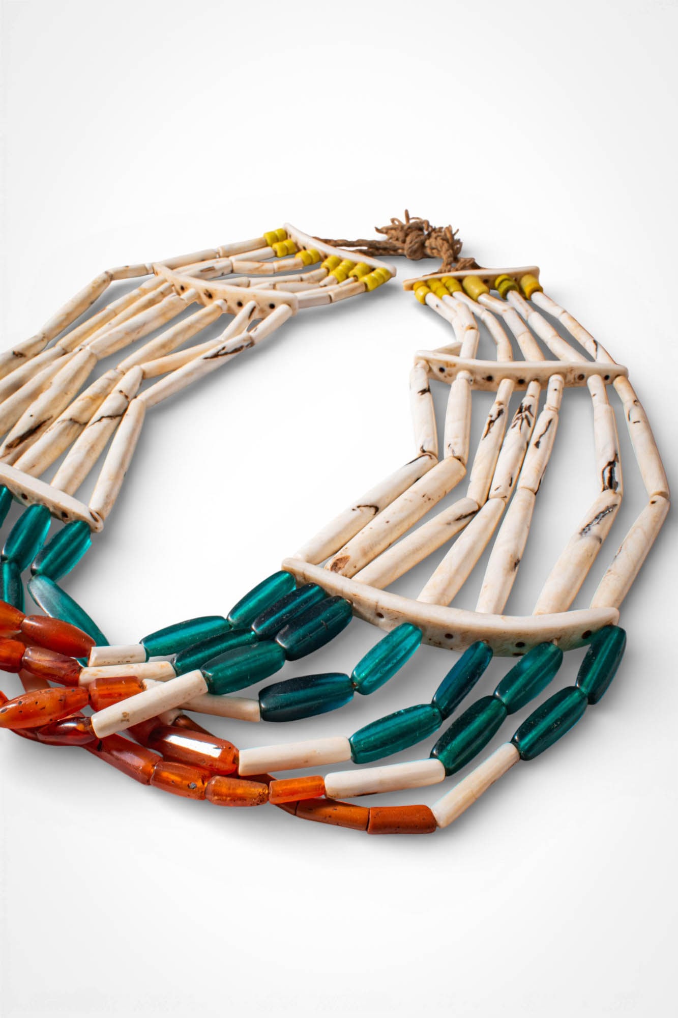 INDIAN NAGALAND POLYCHROME NECKLACE: Ca. 19th - 20th century AD. >A necklace composed of two curved bone spacer panels from which multiple elongated shell pendants are suspended. Below these elements are several strands of glass beads ar