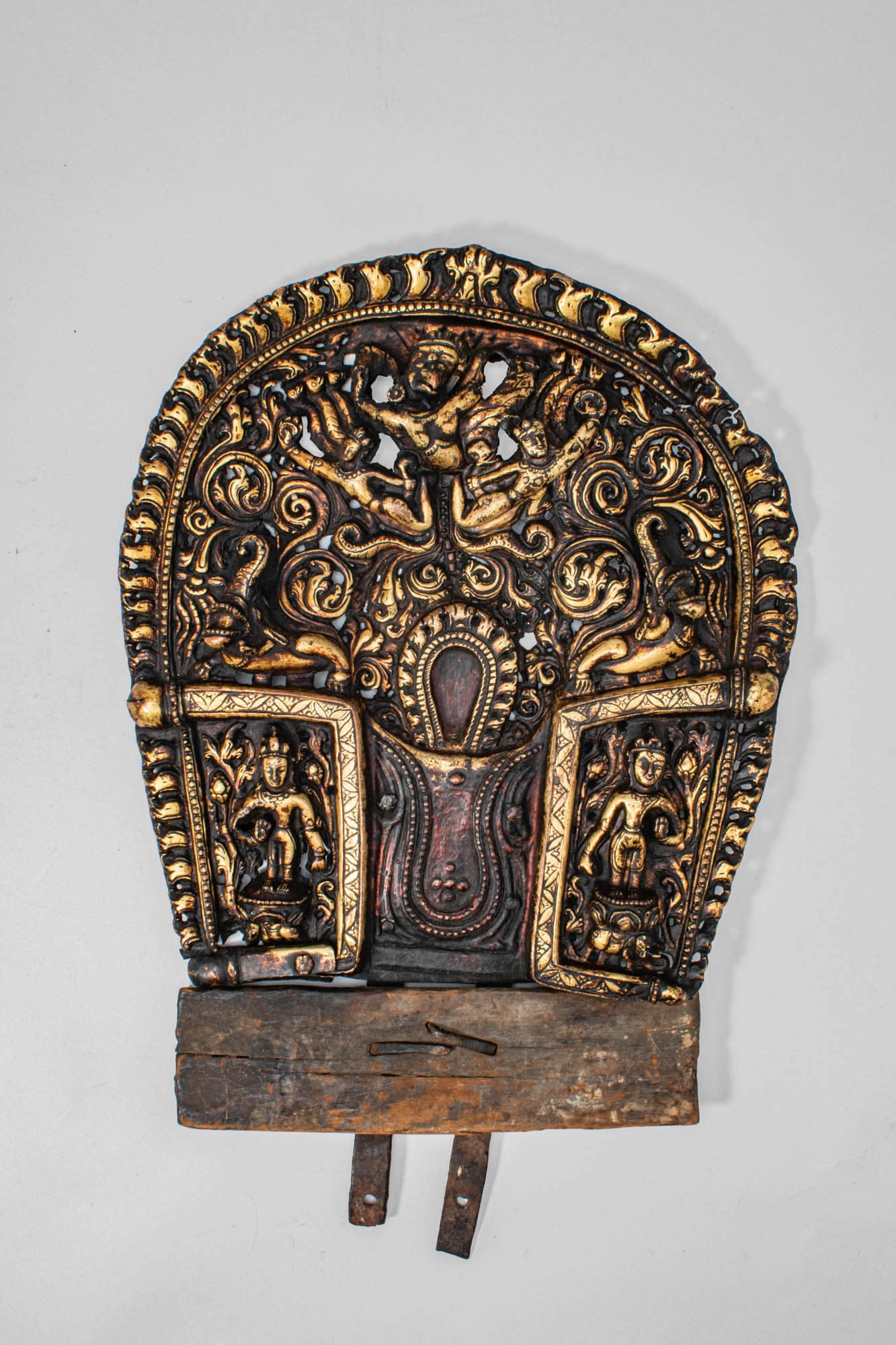 NEPALESE REPOUSS? GILT COPPER MANDORLA: Ca. 15th century AD. A finely worked Nepalese gilt-copper repouss? mandorla, richly decorated in high relief with scrolling foliage, celestial figures, and auspicious motifs. The central niche, former
