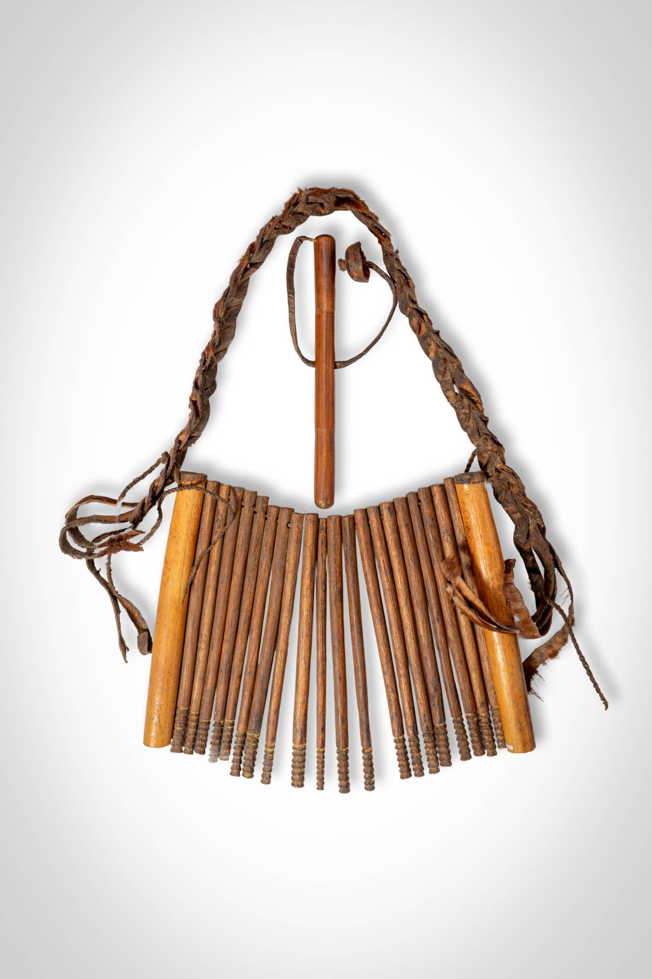 ASMAT NECKLACE: Ca. 19th - 20th century AD. >A large neck ornament composed of numerous slender wooden elements suspended from a braided fibre cord. The pendants are arranged in a radiating formation, each carefully