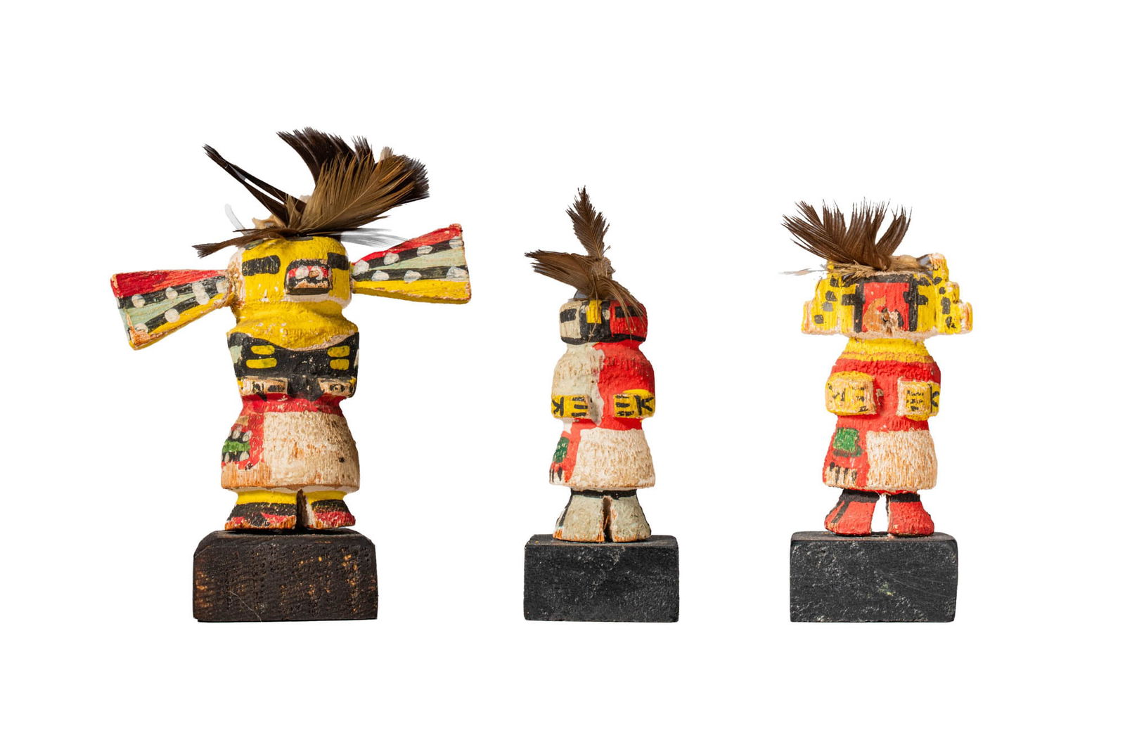 GROUP OF THREE MINIATURE KACHINA DOLLS: Ca. 20th century AD. >A group comprising three miniature kachina dolls, each modelled as a standing figure. The figures are decorated with bright painted pigments in red, yellow, black, and white, for