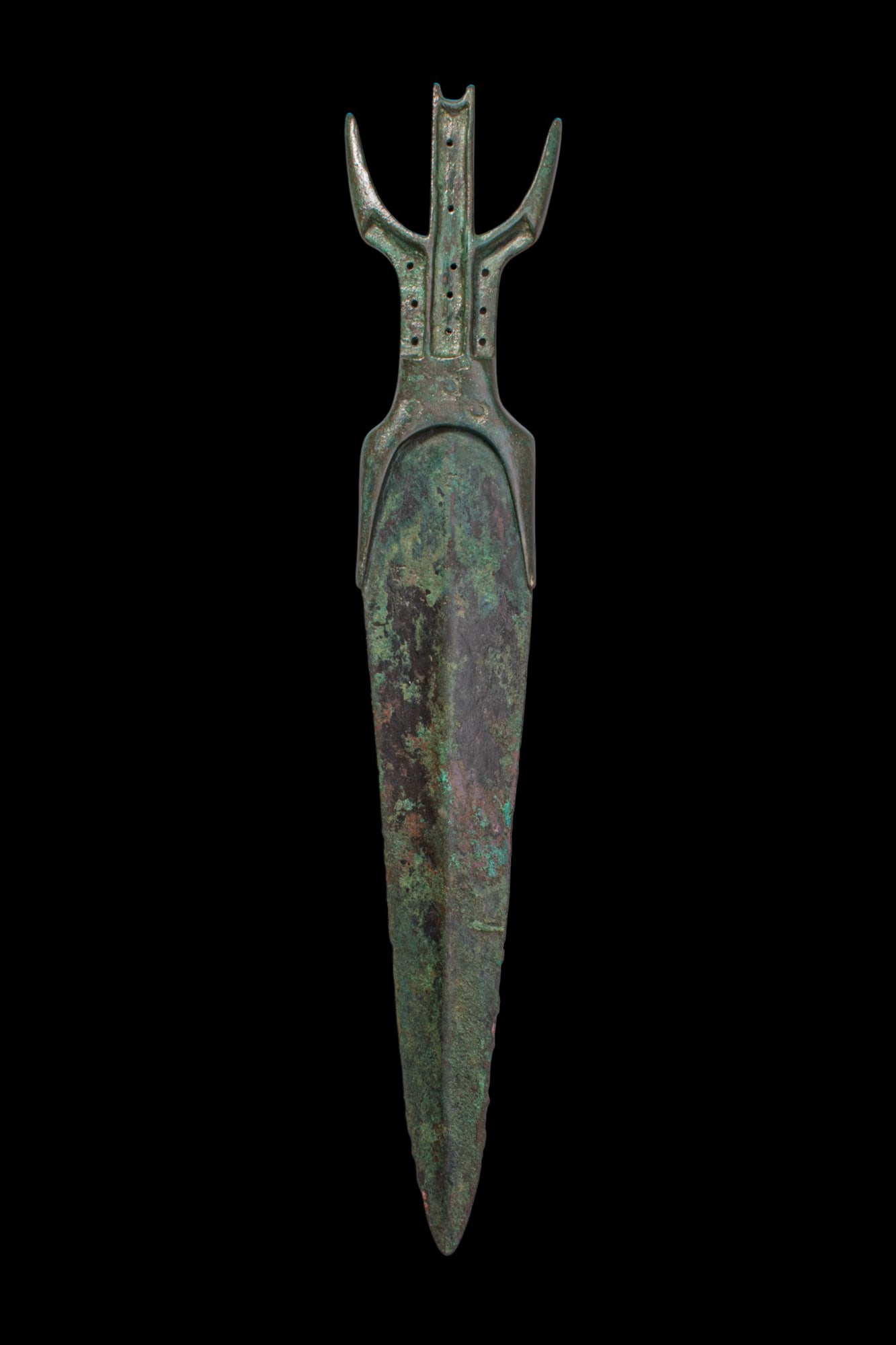 RARE EGYPTIAN BRONZE DAGGER: Middle Kingdom, Ca. 2055 - 1790 BC. A bronze dagger with a tapering blade and broad shoulder, both faces with pronounced midrib. The hilt has a central stem flanked by a pair of upturned lateral prong