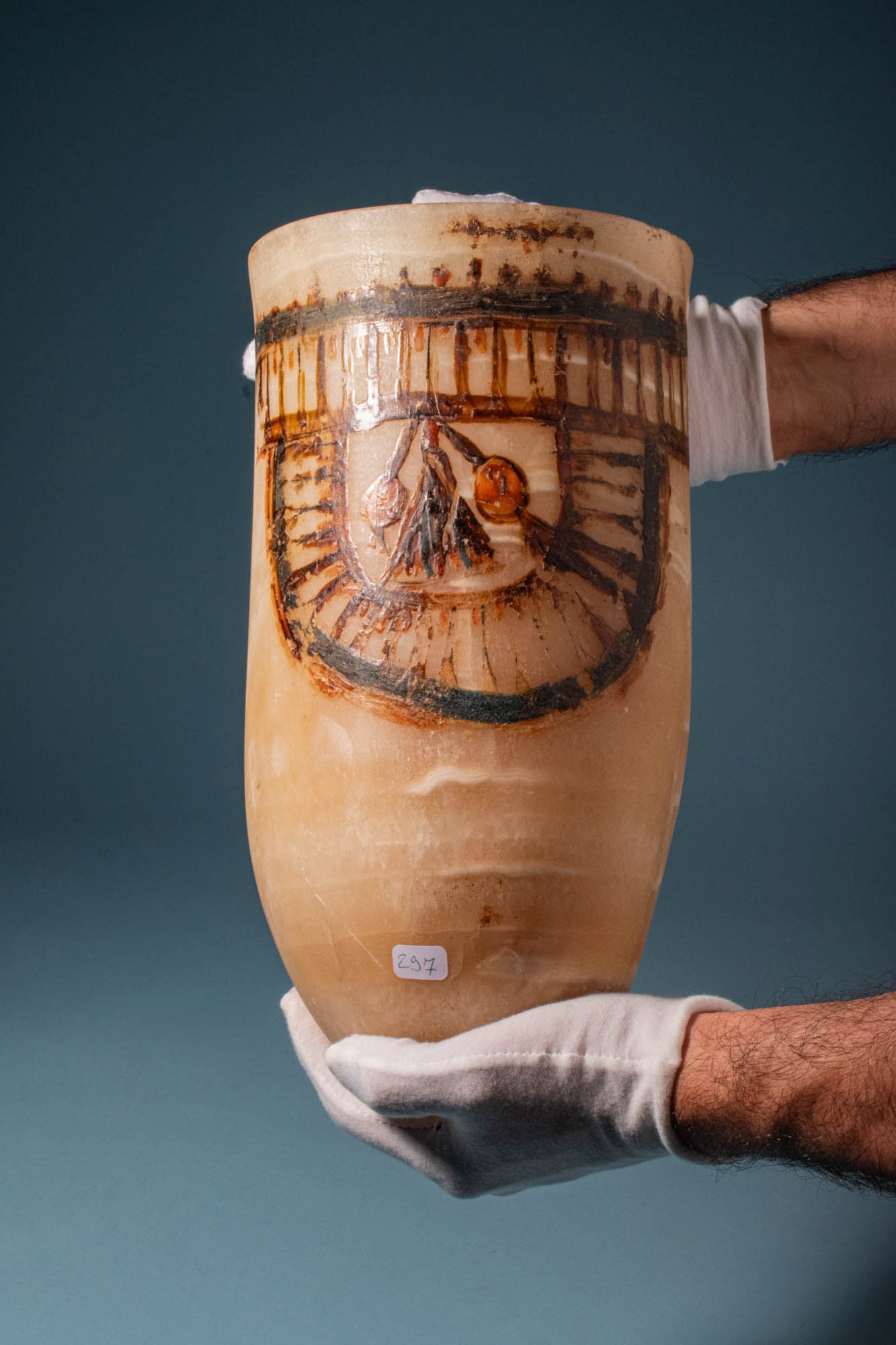 MAGNIFICENT EGYPTIAN PAINTED ALABASTER CERIMONIAL JAR: New Kingdom, Ca. 1550 - 1069 BC. A ceremonial jar carved from alabaster with a tubular body ending in a rounded base and a straight cylindrical rim. The upper portion is decorated with a painted friez