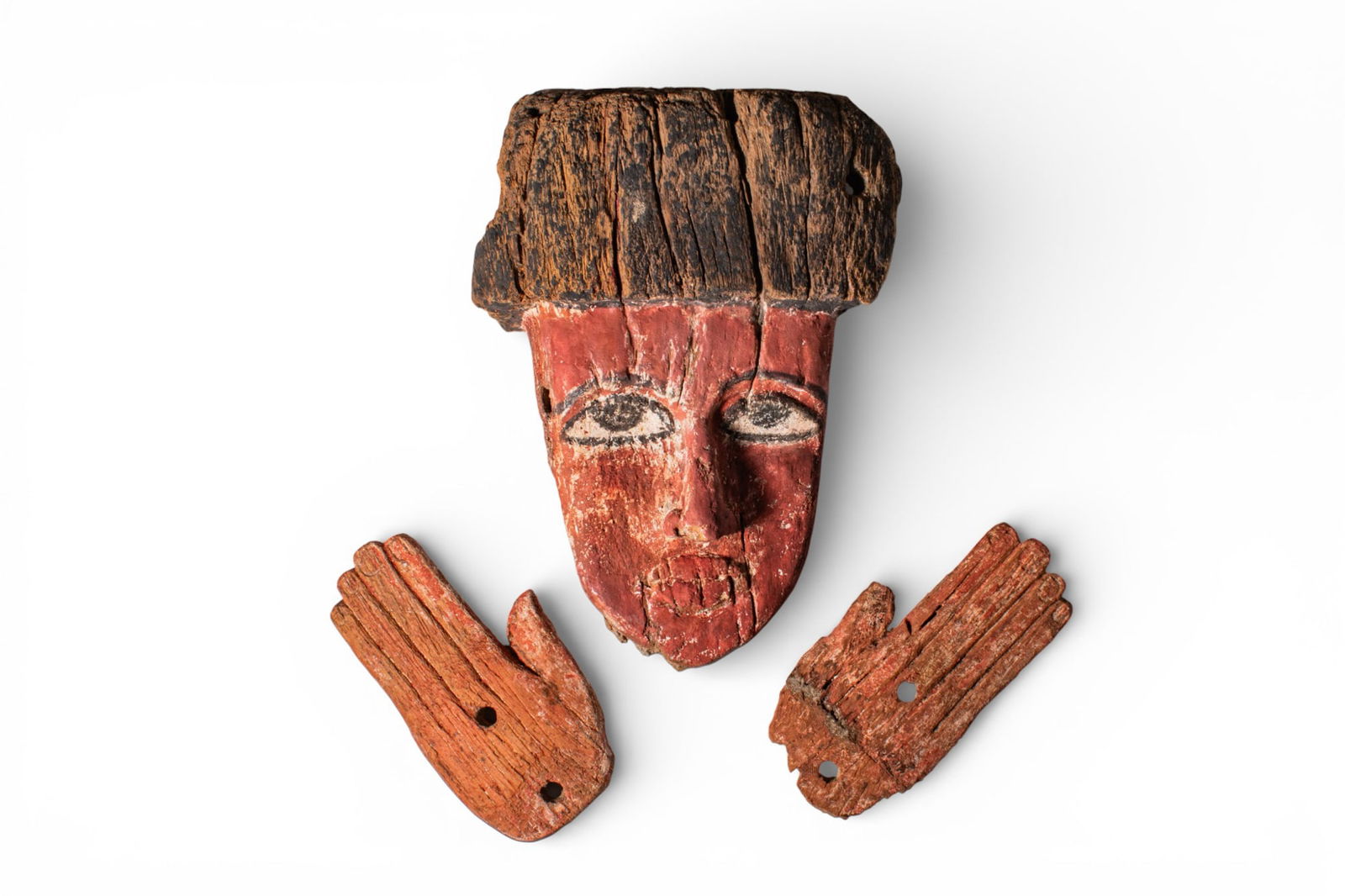 INTERESTING COLLECTION OF EGYPTIAN FUNERARY ELEMENTS FROM A POLYCHROME COFFIN: Late Period to Ptolemaic Period, Ca. 664 - 30 BC. A collection of wooden funerary elements, including: a coffin mask with a black-painted headdress, a red-painted visage, large eyes, protruding nose a