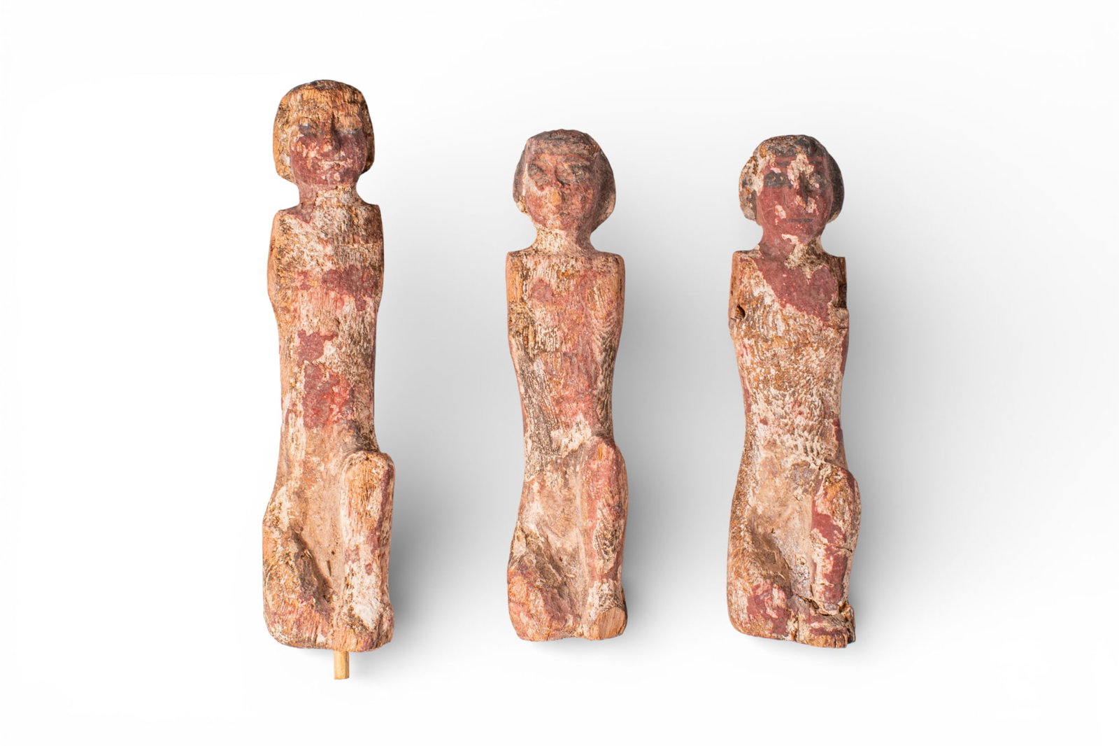 COLLECTION OF EGYPTIAN WOODEN ROWERS: Middle Kingdom, Ca. 2055 - 1790 BC. A collection of three wooden rowers, each carved as a male figure kneeling on the right knee, with a short wig and a long, tapering body. The bodies are painted in