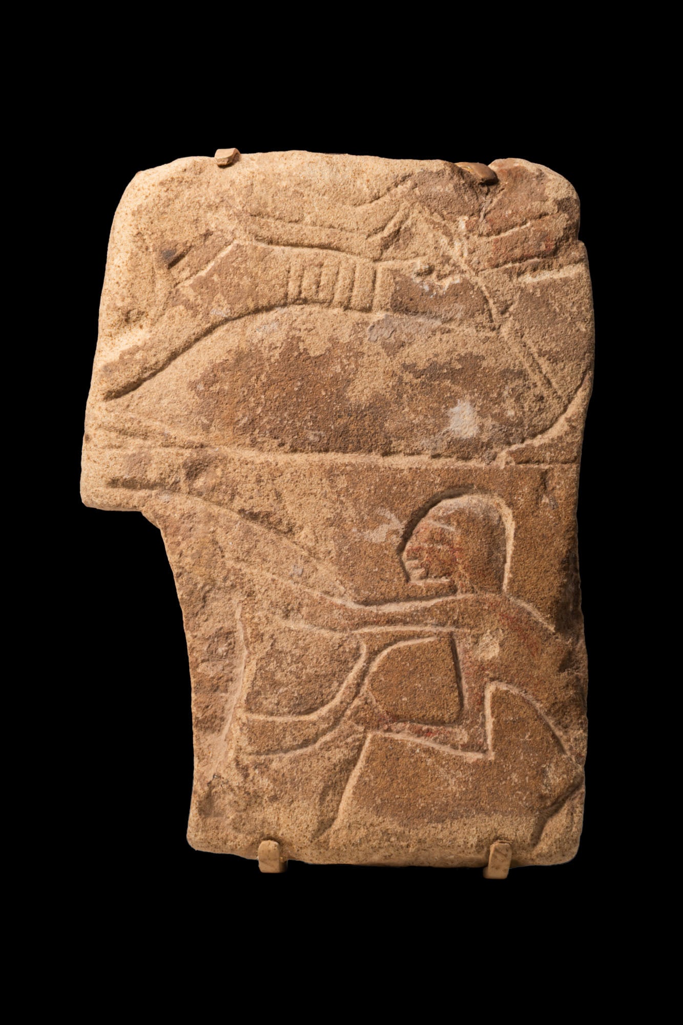 EGYPTIAN SANDSTONE RELIEF OF A DRIVER ON CART: New Kingdom, Ca. 1550 - 1069 BC. A sandstone relief block carved in sunk relief with a striding cart driver facing left, arms outstretched holding the reins.For similar see: The Metropolitan Museum of