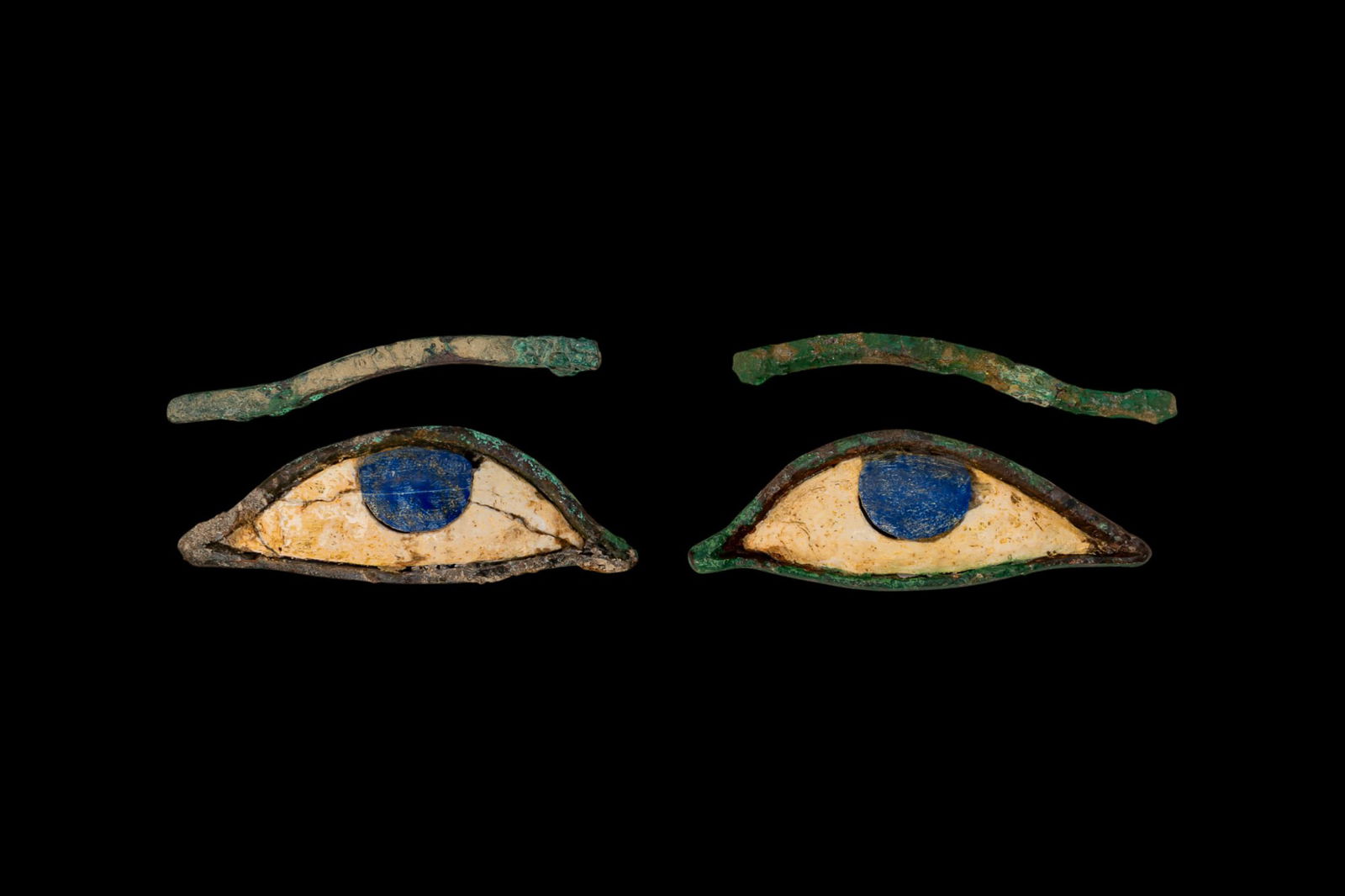 PAIR OF EGYPTIAN EYE INLAYS AND EYEBROWS: Late Period, Ca. 664 - 30 BC. A matching set of mummy inlays comprising a pair of eyes and brows. Each eye is constructed from a bronze frame with a white stone sclera and a circular blue stone iris.