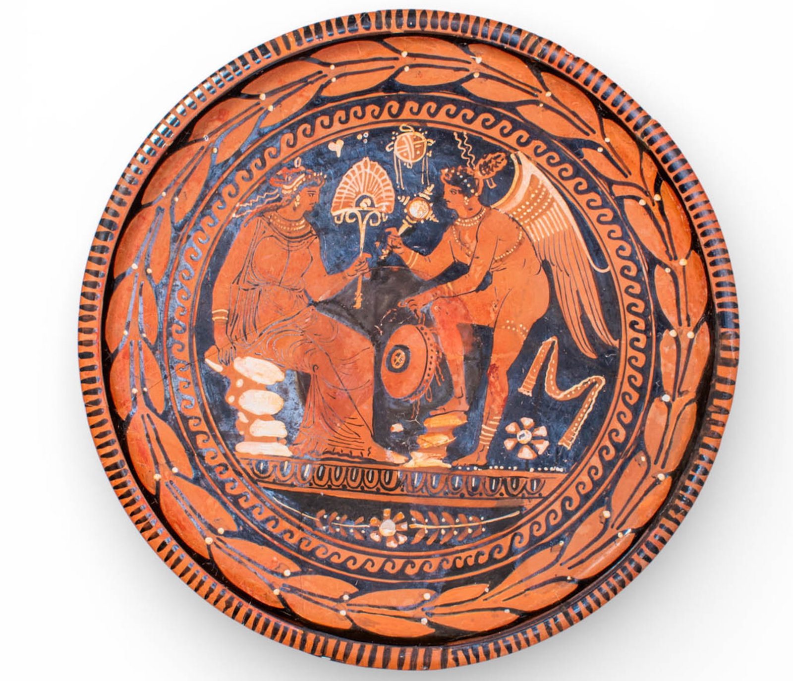 LARGE APULIAN RED-FIGURE DISH WITH WINGED VICTORY, ATTRIBUTED TO THE CIRCLE OF THE BALTIMORE PAINTER: Ca. 330 - 300 BC. A red-figure pottery patera attributed to the circle of Baltimore Painter. The large bowl is shallow with a flattened rim and stands on a low ring foot. The interior is decorated wit