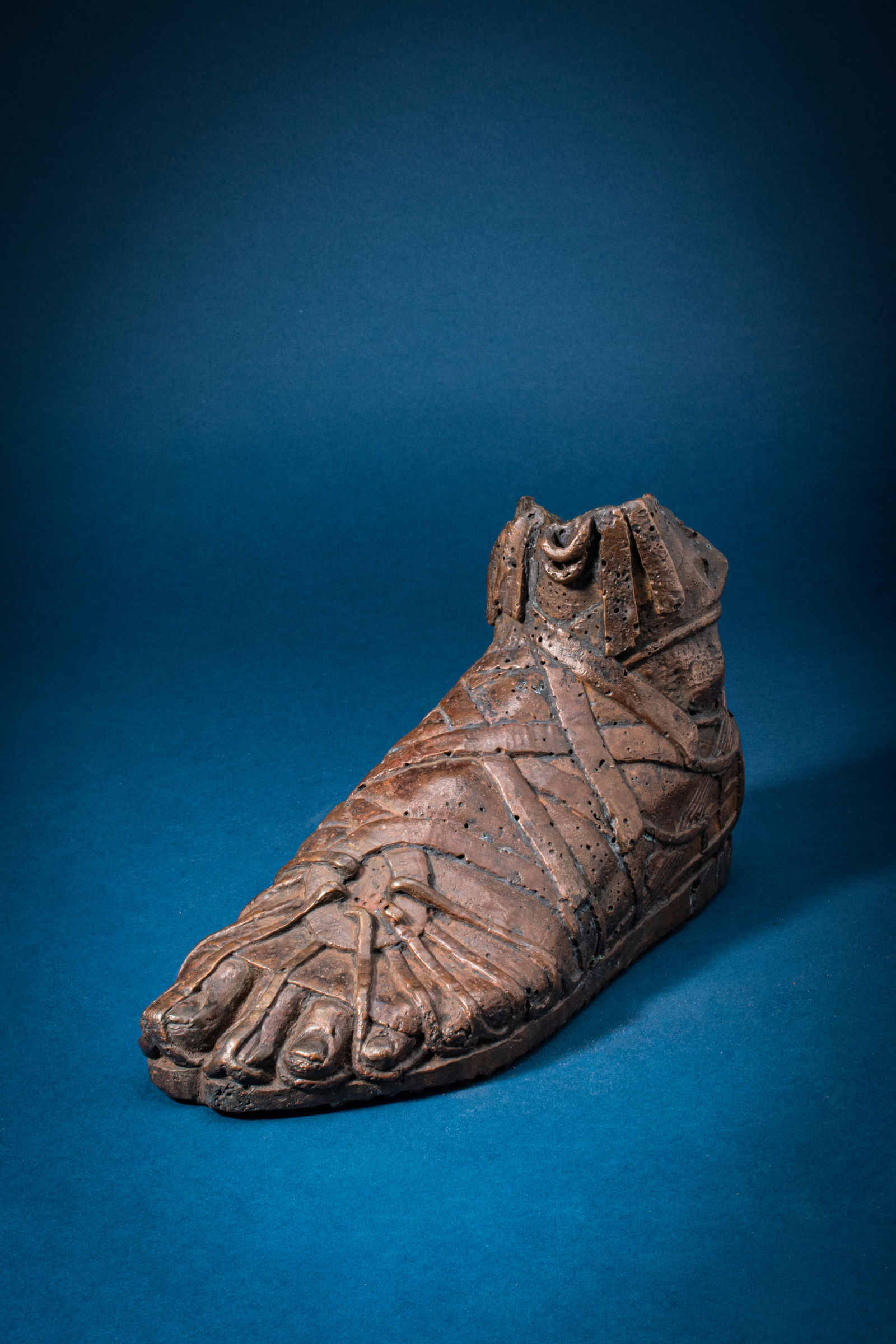 RARE LIFE-SIZE ROMAN BRONZE SANDALED FOOT OF A CAVALRY SOLDIER: Ca. AD 200 - 400. A life-size, hollow-cast bronze foot with individually modelled toes, wearing a sandal rendered with criss-crossing straps over the instep and bindings across the forefoot, with over