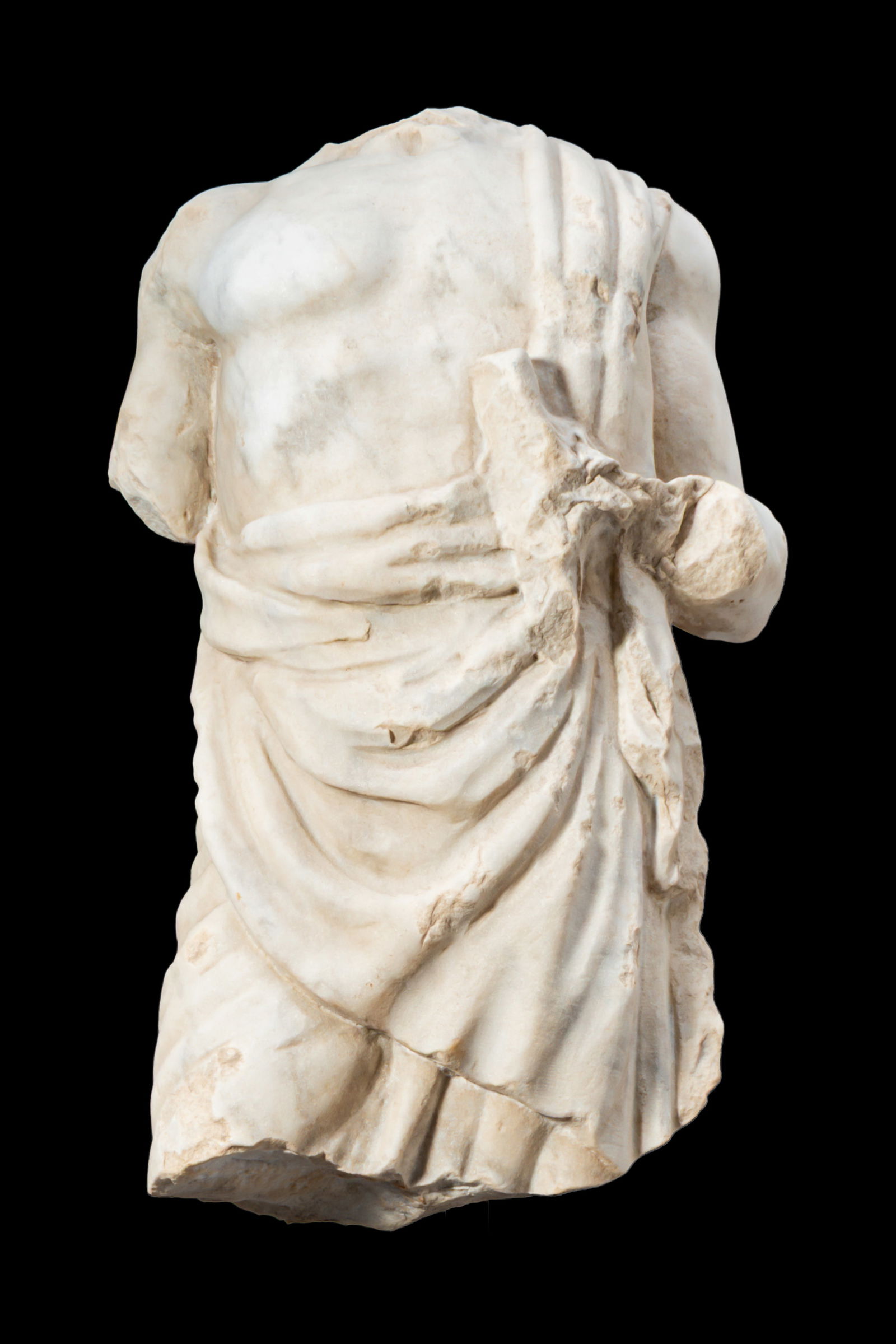 ROMAN MARBLE STATUE OF TOGATUS: Ca. AD 1 - 300. A marble torso of a togatus, wrapped in a toga draped diagonally across the chest and over the left shoulder, the fabric arranged in deep, stacked folds over the abdomen and gathered a