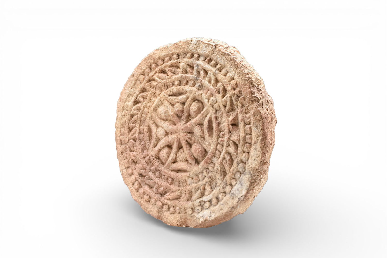 BYZANTINE LIMESTONE ARCHITECTURAL ROUNDEL WITH CROSS: Ca. AD 500 - 600. A limestone architectural roundel carved in relief with a central cross with flaring arms and pellets in the spandrels. A narrow beaded ring encircles the cross, followed by a band o