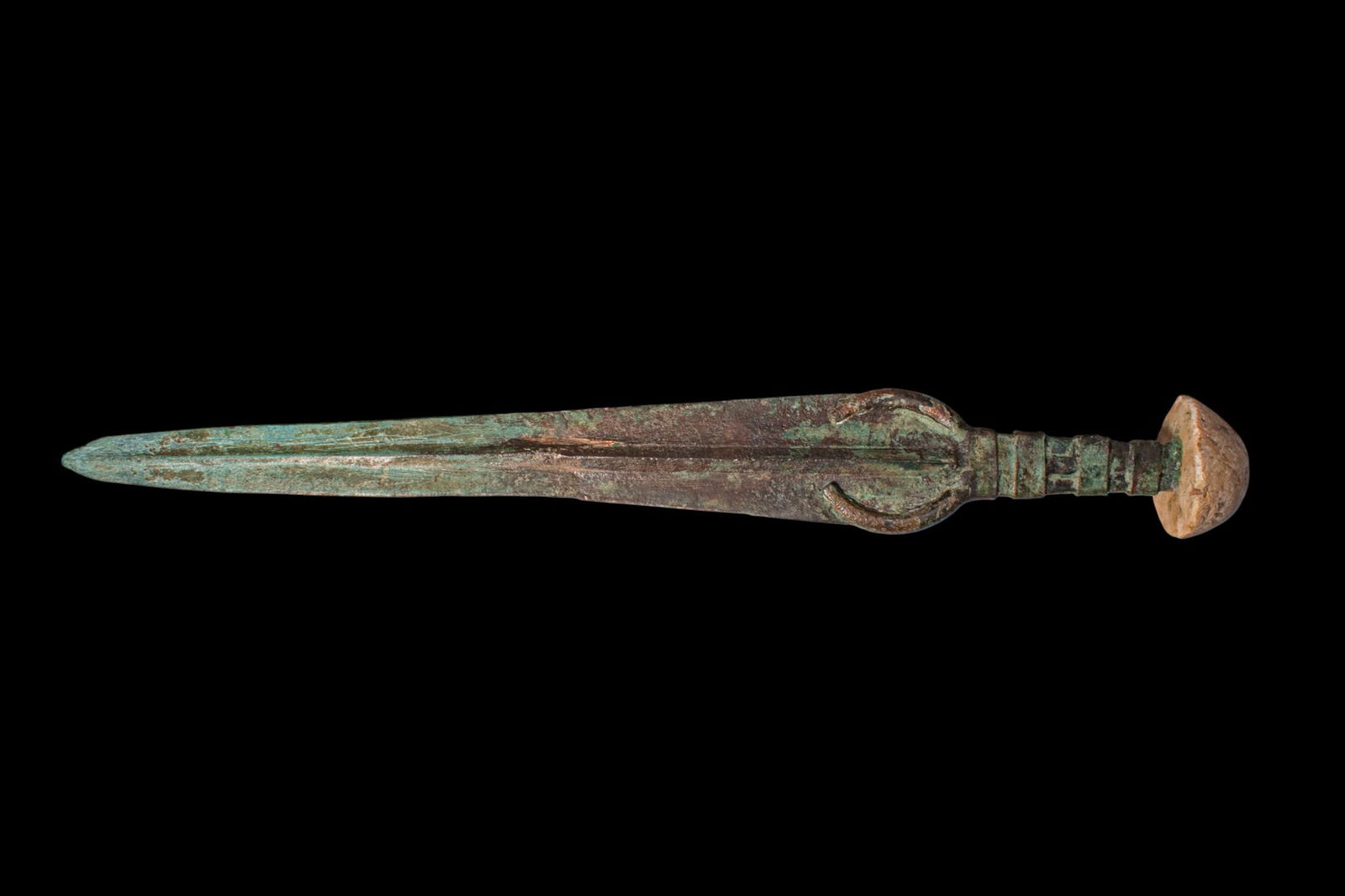 BRONZE AGE / EARLY GREEK PERIOD BRONZE SWORD WITH STONE POMMEL: Ca. 1200 - 800 BC. A bronze sword with a long, tapering blade of lenticular section with a pronounced midrib running towards the point. The banded hilt terminates in a stone pommel of biconvex profile
