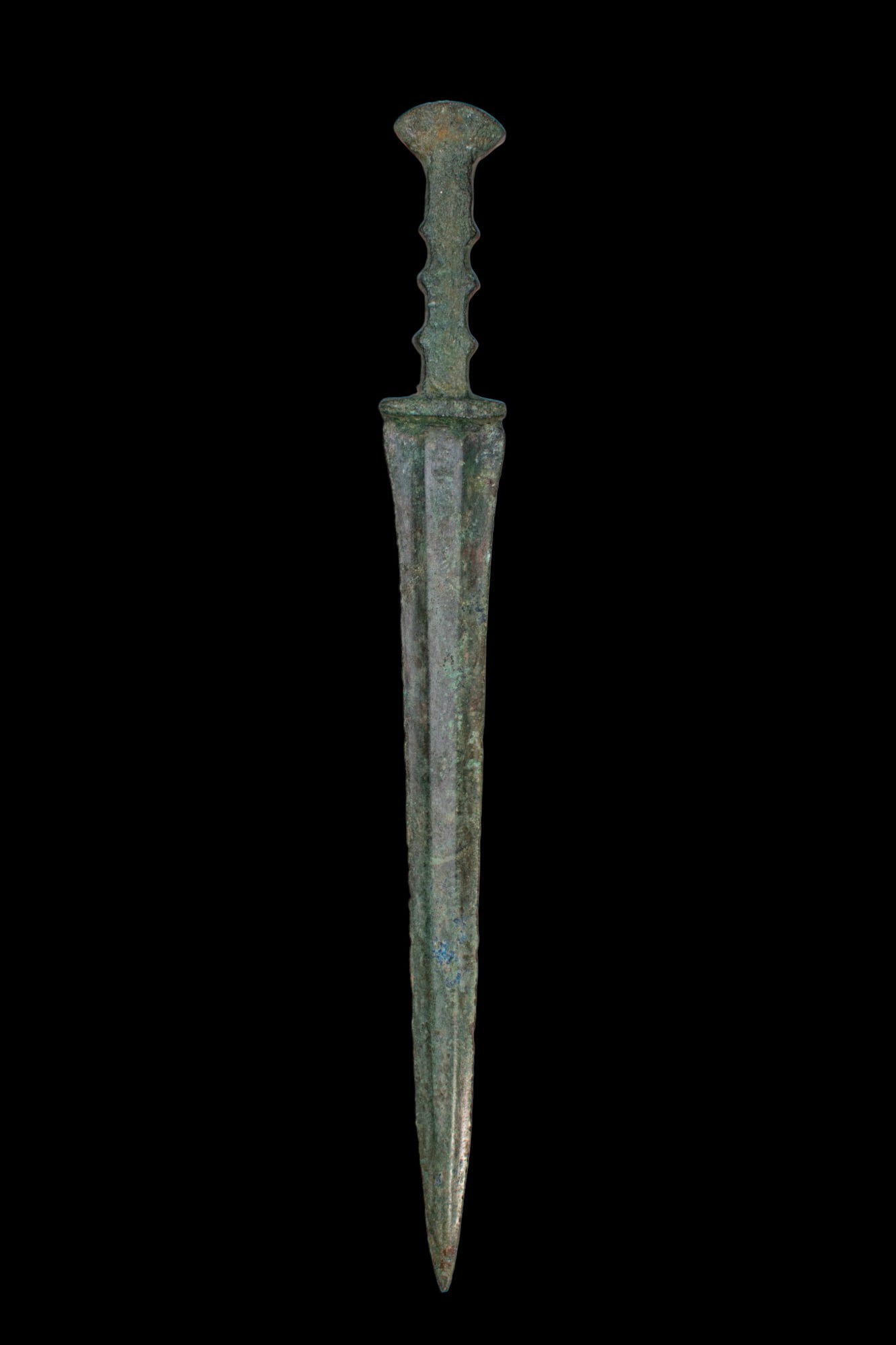 BRONZE AGE / EARLY GREEK PERIOD BRONZE SWORD: Ca. 1200 - 800 BC. A bronze sword with an integral hilt with a flaring pommel and a grip with a series of shallow scalloped notches along each side. The blade is long and tapering with a pronounced mi