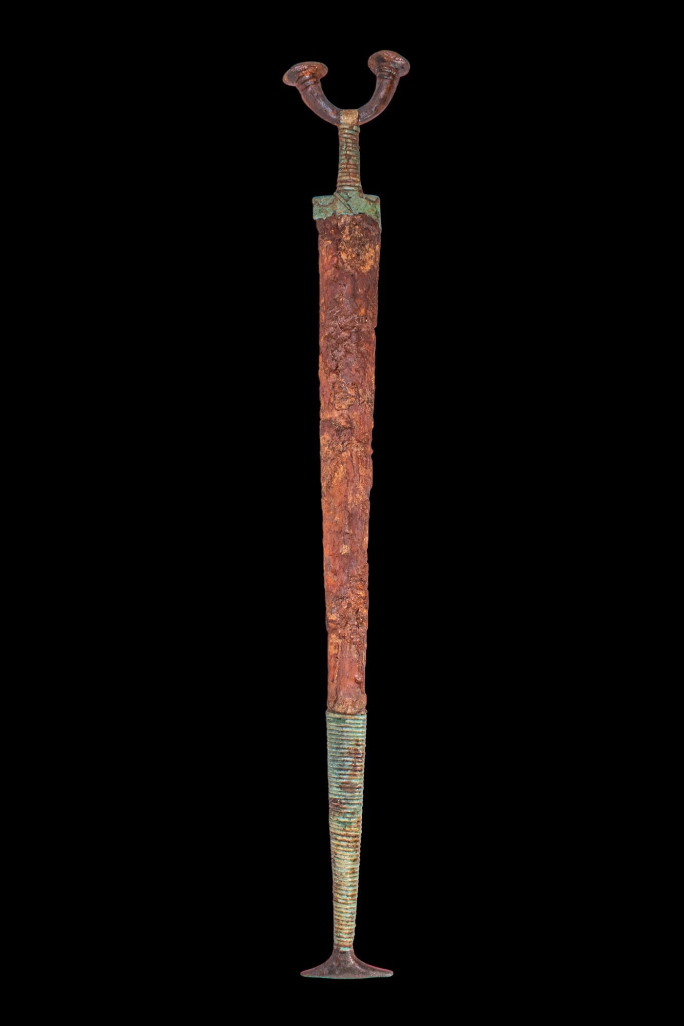 RARE CELTIC IRON AND BRONZE SWORD WITH SCABBARD: Ca. 600 - 500 BC. An iron and bronze sword with a long, tapering iron blade, fitted with a bronze scabbard with a flaring chape. The hilt has a short, ribbed grip and a bifurcated pommel, each arm ter
