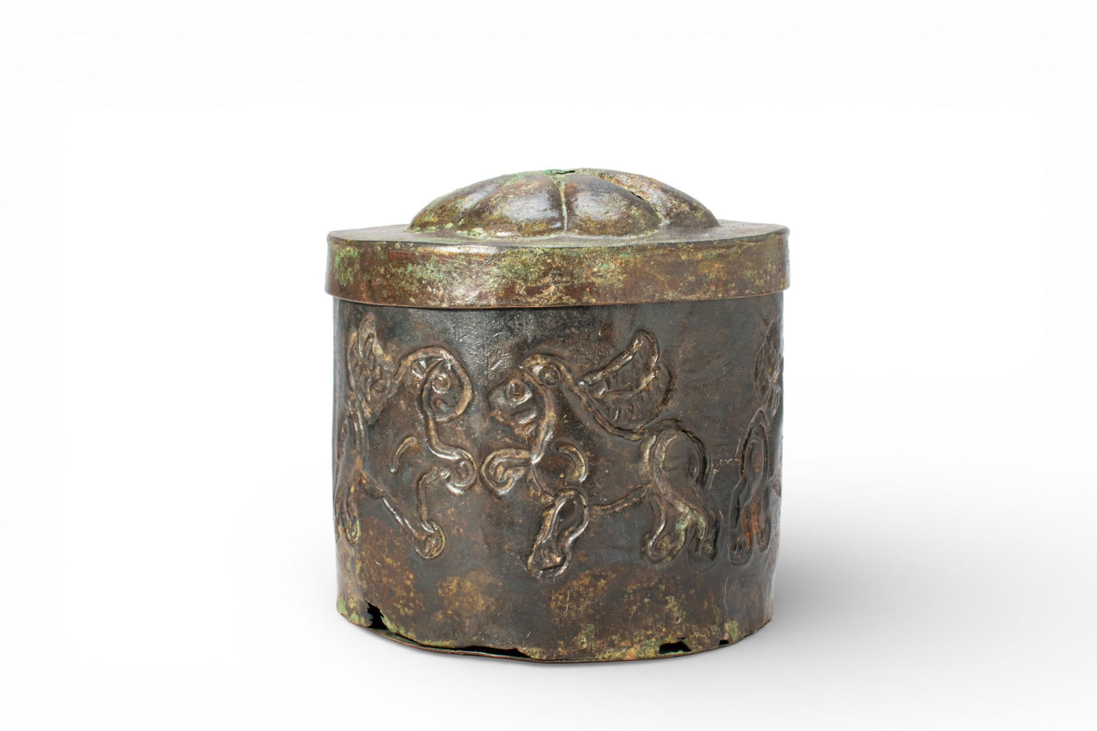 GREEK PERIOD BRONZE PYXIS WITH WINGED HORSES: Ca. 600 - 400 BC. A bronze pyxis of cylindrical form with a close-fitting lid rising to a domed crown with a radiating rosette in relief. The body is decorated in relief with a continuous frieze of wi