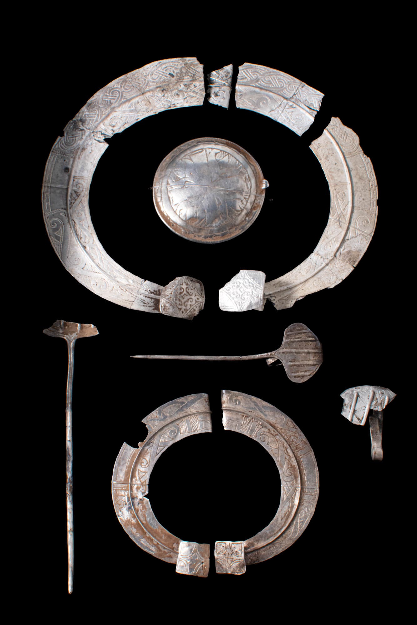 PAIR OF BALTIC VIKING SILVER BROOCHES AND MEDALLION: Ca. AD 700 - 900. A pair of two large silver Viking brooches with niello and a silver medallion. The external band of the brooches are embellished with intricate phytomorphic and vegetal motifs. The i