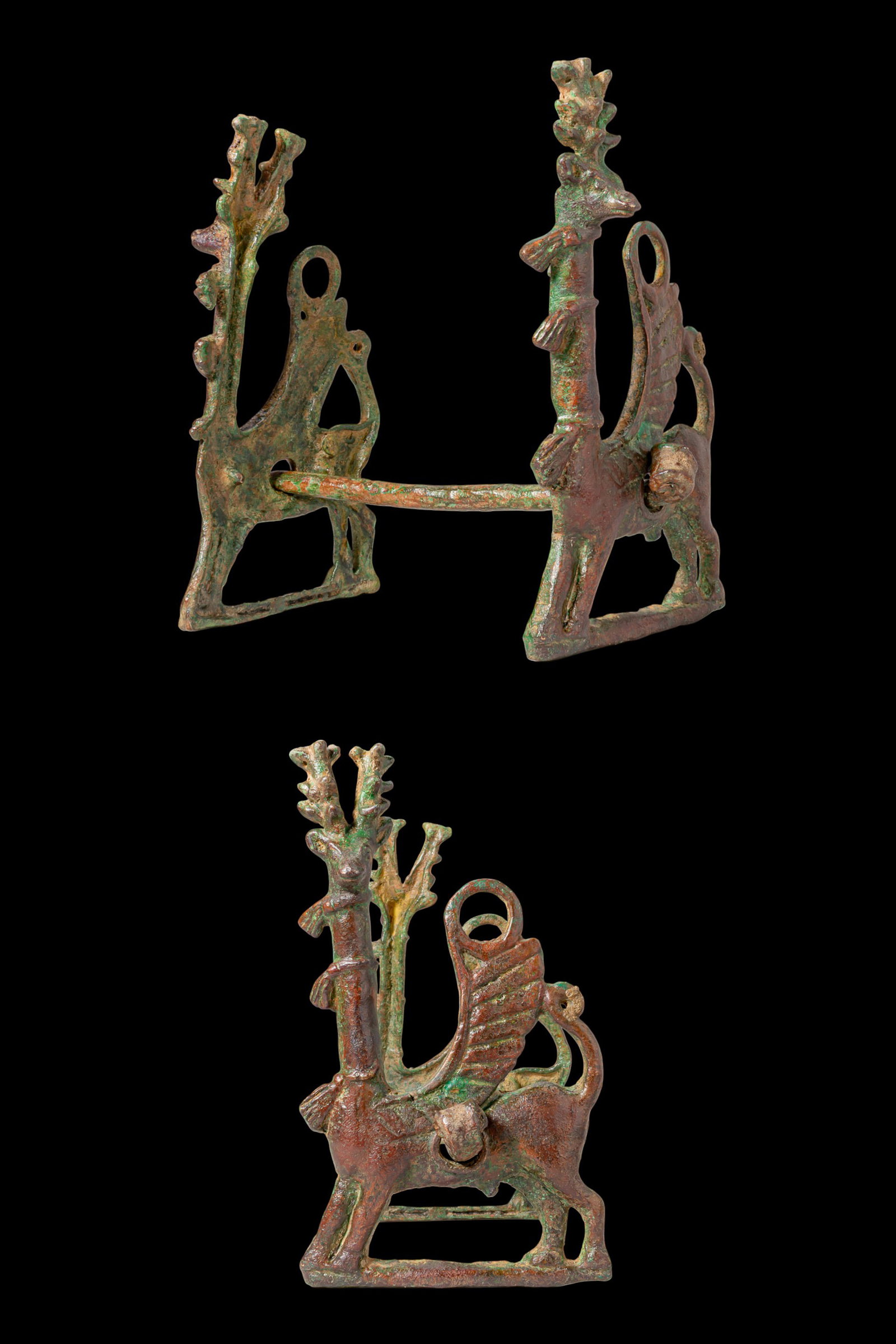 BRONZE AGE BRONZE HORSE BIT WITH WINGED STAGS: Ca. 1200 - 800 BC. A bronze horse bit comprising a straight cylindrical mouthpiece fitted through two openwork cheekpieces, each cast as a winged stag standing on a rectangular base frame, with a long