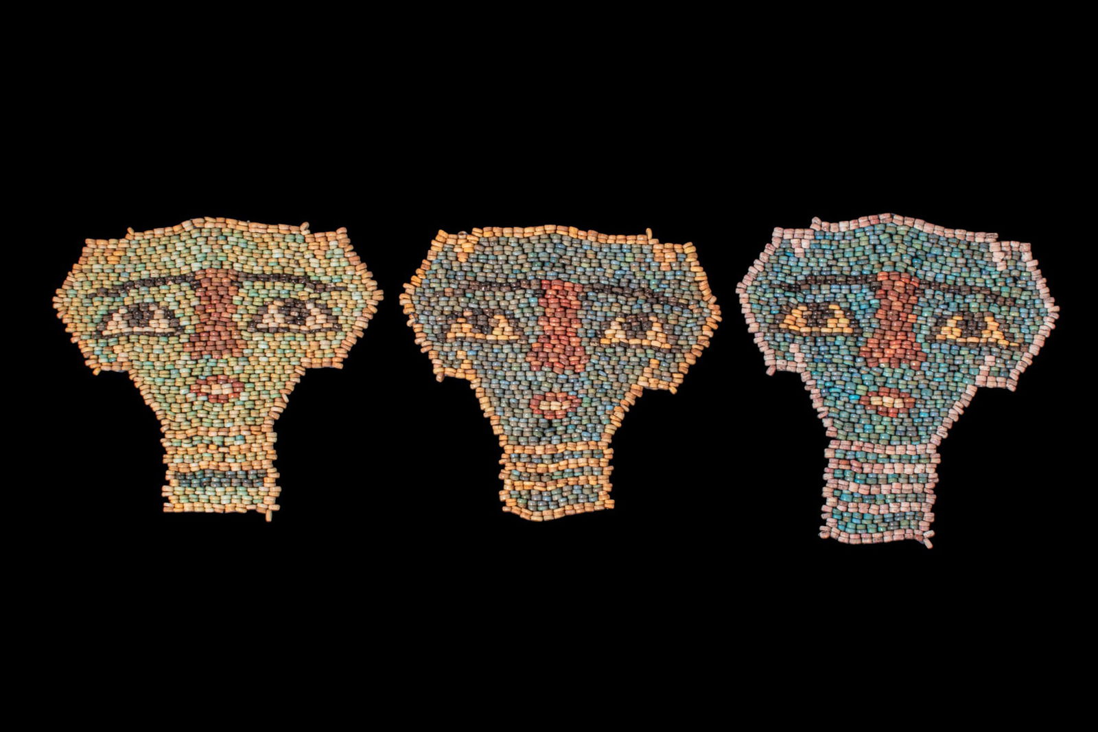 COLLECTION OF EGYPTIAN FAIENCE BEADED MUMMY MASKS: Late Period, Ca. 664 - 30 BC. A collection of three faience mummy masks, each restrung as a polychrome beaded face panel with a striped beard below, thin brows, almond-shaped eyes with white sclera an
