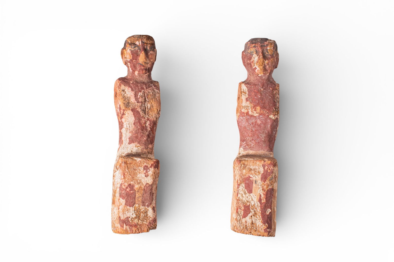 PAIR OF EGYPTIAN WOODEN ROWERS: Middle Kingdom, Ca. 2055 - 1790 BC. A pair of wooden rowers, each carved as a seated male figure with a rounded head and short wig. The shoulders are drilled laterally for the attachment of separate a