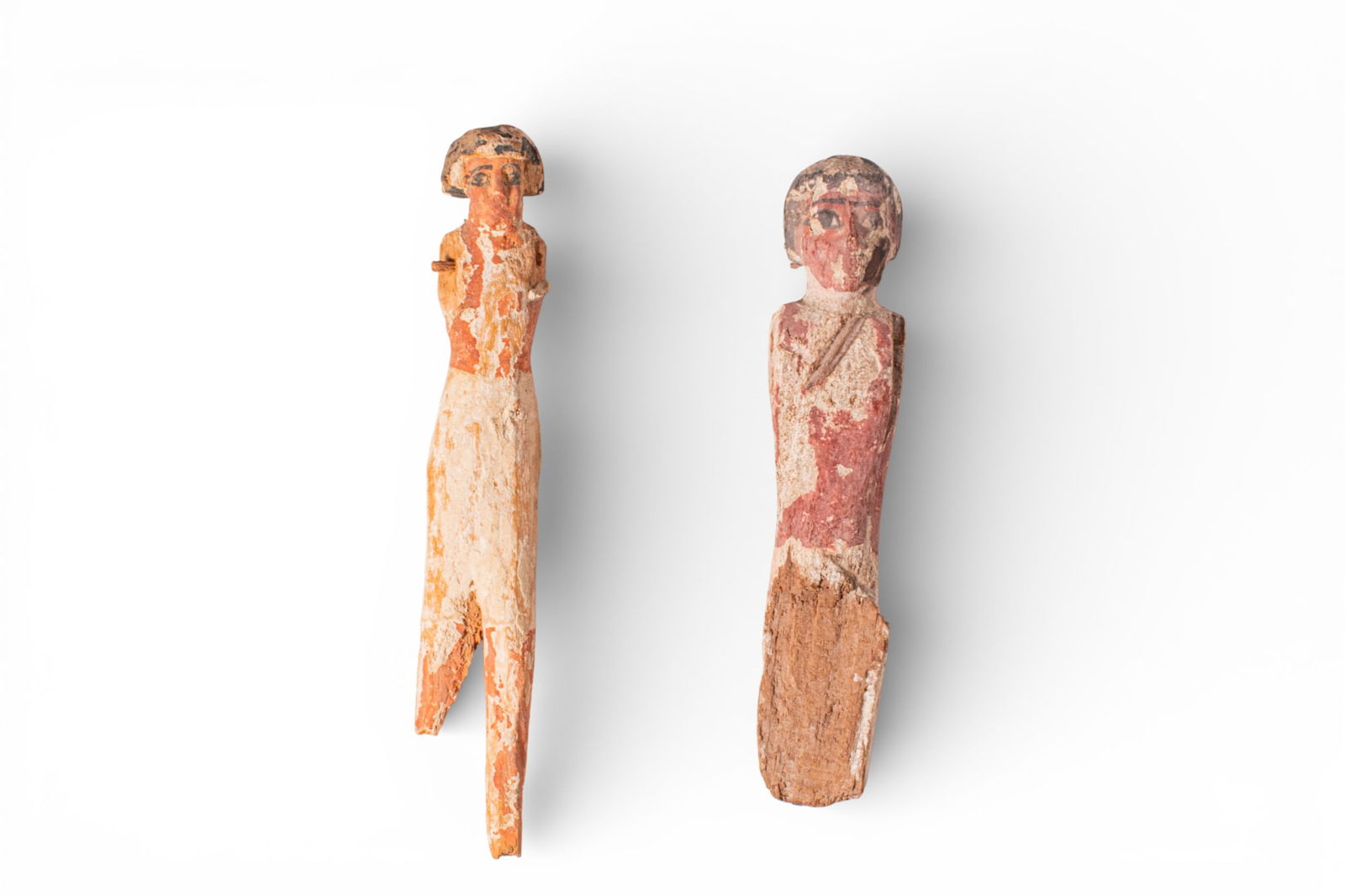 PAIR OF EGYPTIAN WOODEN ROWERS: Middle Kingdom, Ca. 2055 - 1790 BC. A pair of wooden rowers, each painted red over a white gesso, including, from left to right: a slender standing figure with a short wig and an elongated body taperi