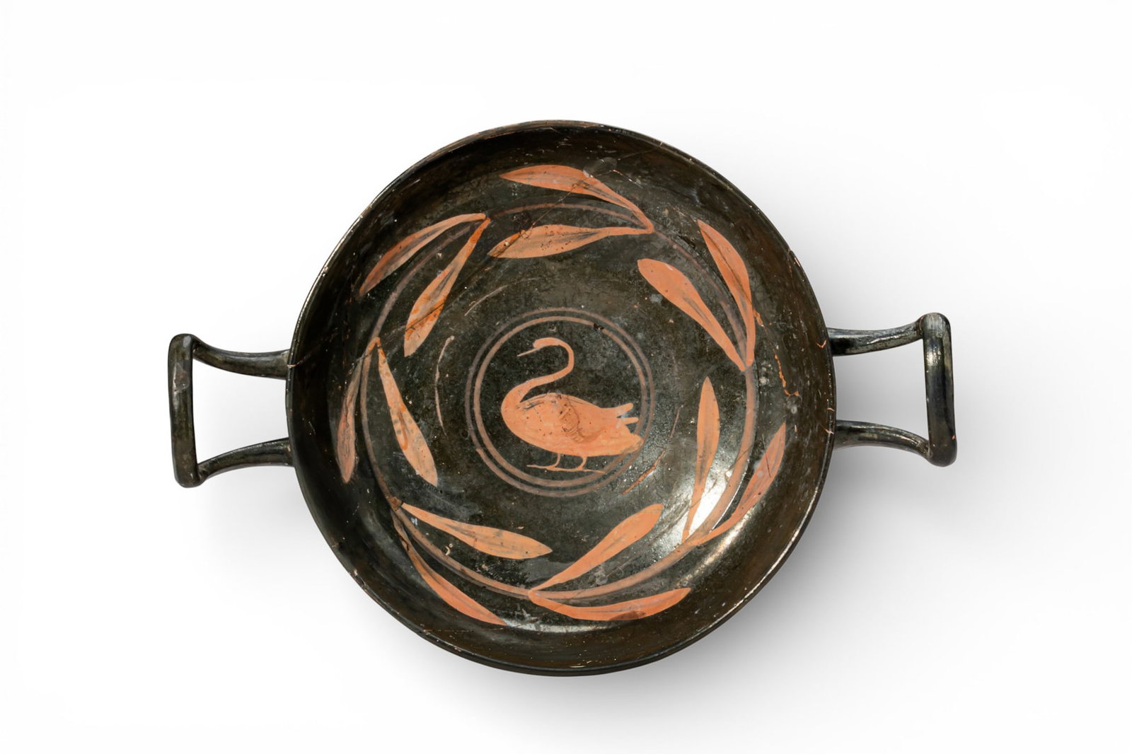 ELEGANT APULIAN RED-FIGURE KYLIX WITH SWAN AND LAUREL WREATH: Ca. 400 - 300 BC. A shallow kylix with a broad open bowl on a low stepped foot and a pair of opposing strap handles. The interior shows a swan in profile within a central medallion framed by concentri