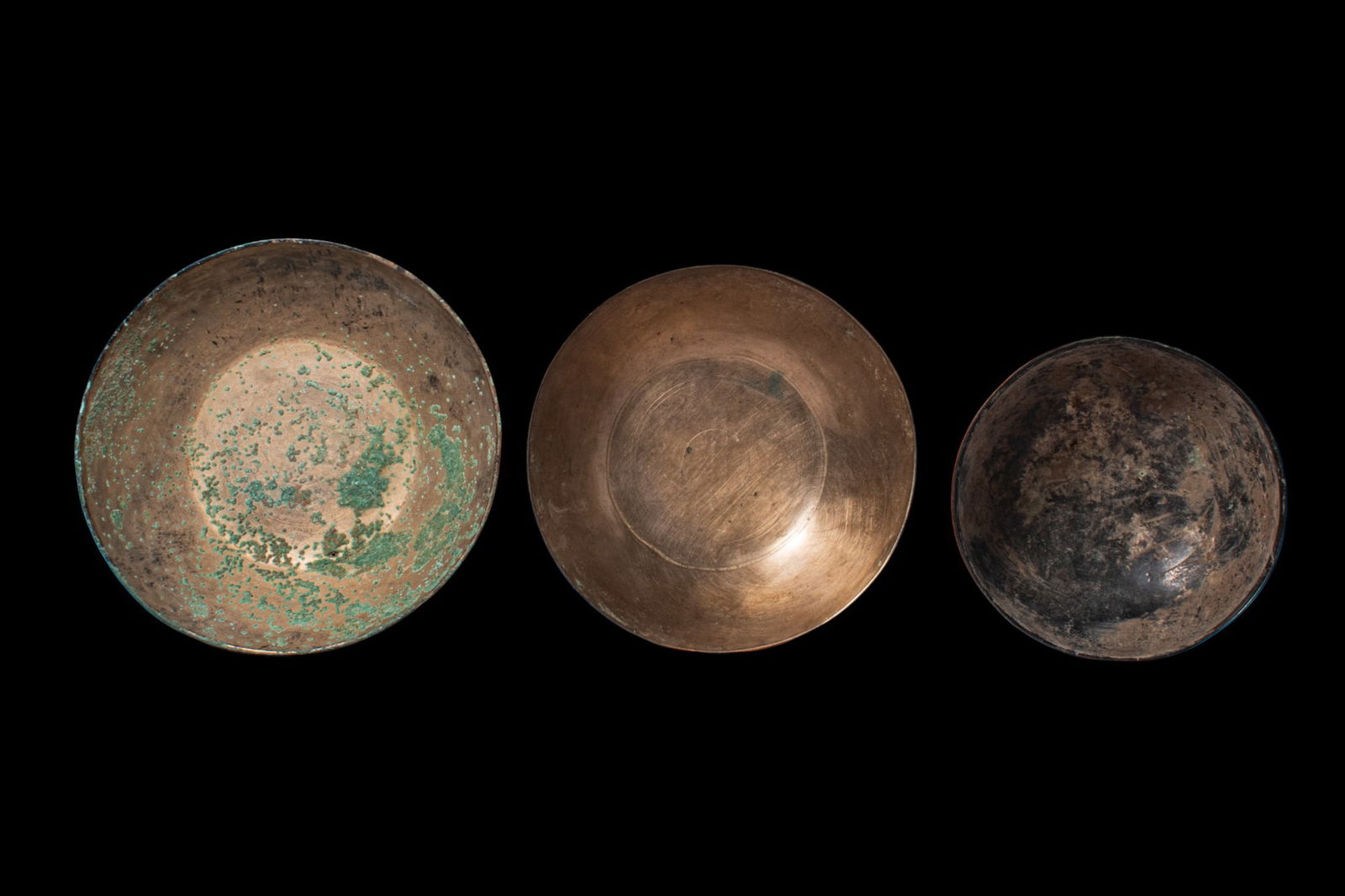 COLLECTION OF GREEK PERIOD BRONZE BOWLS: Ca. 500 BC. A collection of three bronze bowls, including, from left to right: two flat-bottomed shallow bowls with plain rims; and a deeper bowl with a rounded profile. Size: 130-175mm x 50-60mm; Wei
