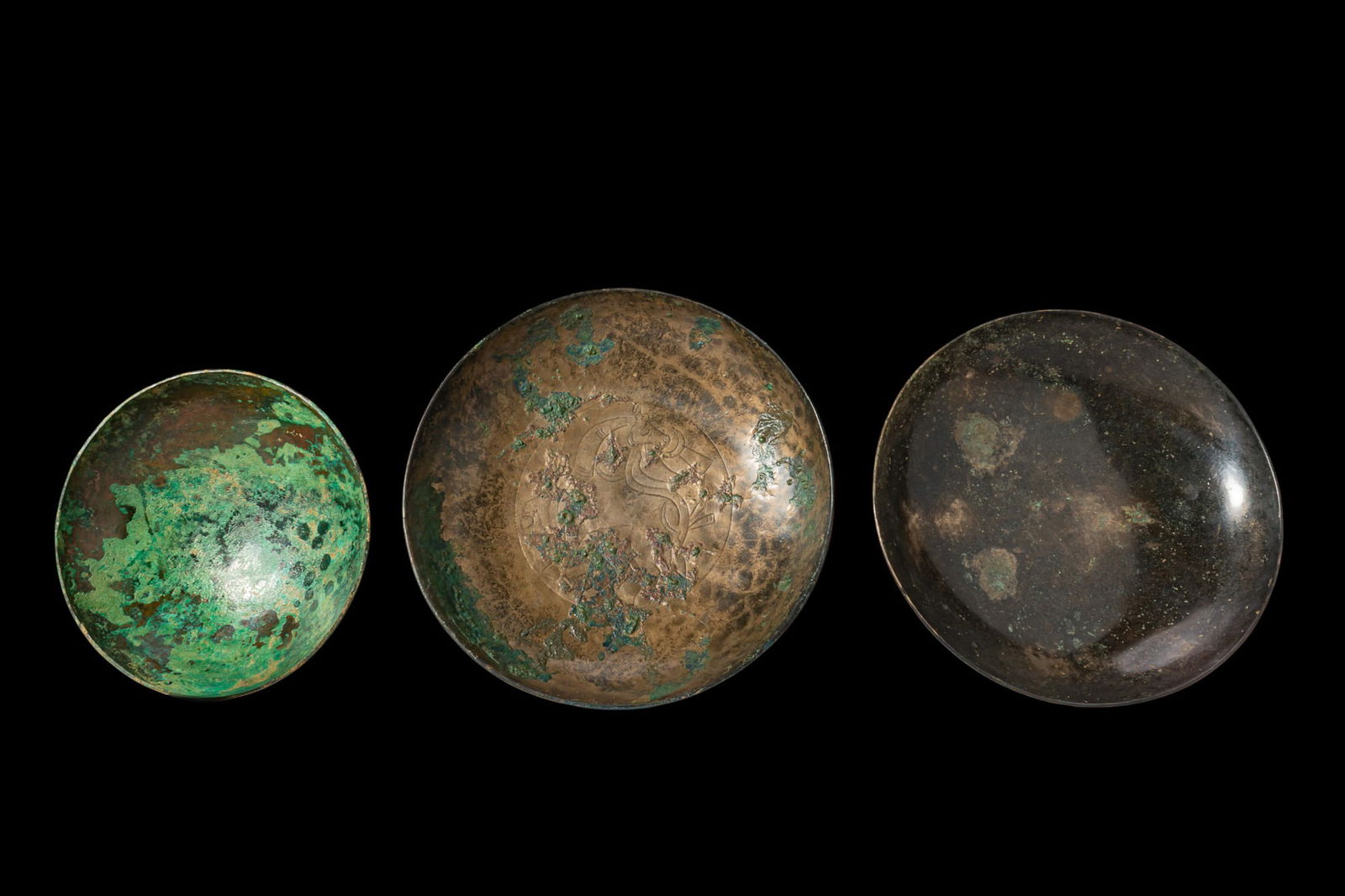 COLLECTION OF GREEK PERIOD BRONZE BOWLS, ONE WITH RUNNING QUADRUPED: Ca. 500 BC. A collection of three bronze bowls, each of shallow circular form with a plain rim and rounded base, the interiors plain except for the central bowl, engraved with a roundel showing a runn