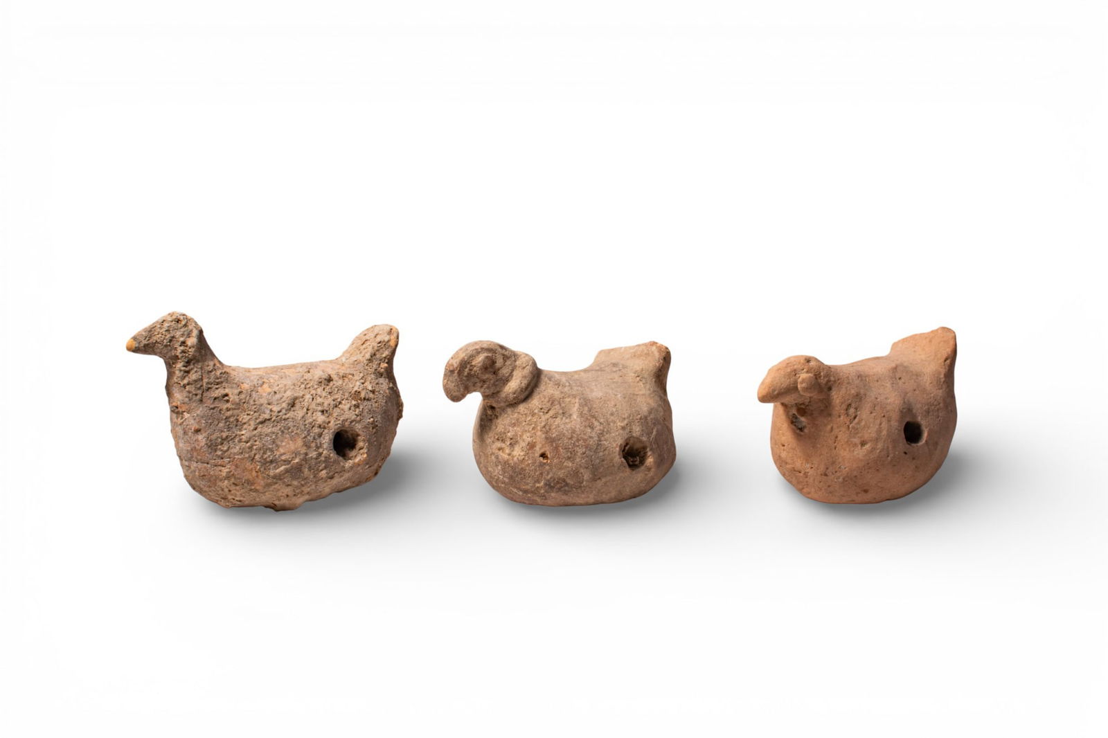 COLLECTION OF GREEK TERRACOTTA DOVES: Ca. 500 - 200 BC. A collection of three terracotta doves, each modelled in the round with a compact body and an upright tail, the head set forward with a short beak. Each figure has a circular perfora