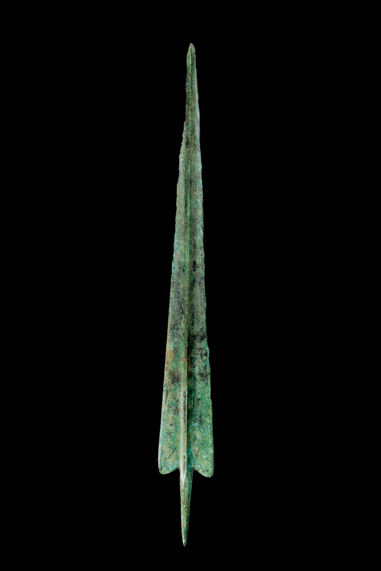 GREEK BRONZE SPEARHEAD: Ca. 1600 - 1300 BC. A bronze spearhead with a slender, tapering blade and a pronounced central ridge, the edges narrowing to a fine point. The ridge continues beyond the blade as an integral tang. 