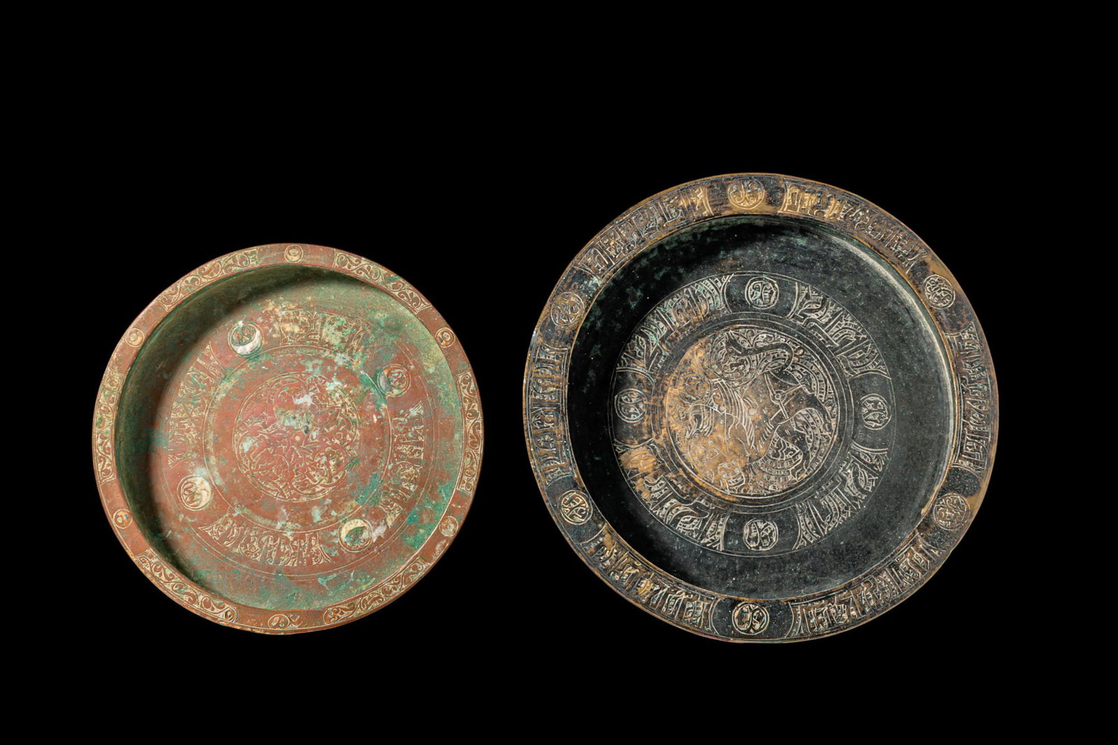 PAIR OF SELJUK BRONZE INSCRIBED TRAYS: Ca. AD 1000 - 1200. A pair of bronze trays, from left to right: a circular shallow dish with a broad everted rim engraved with scrolling ornament and roundels, the well decorated with a central rounde