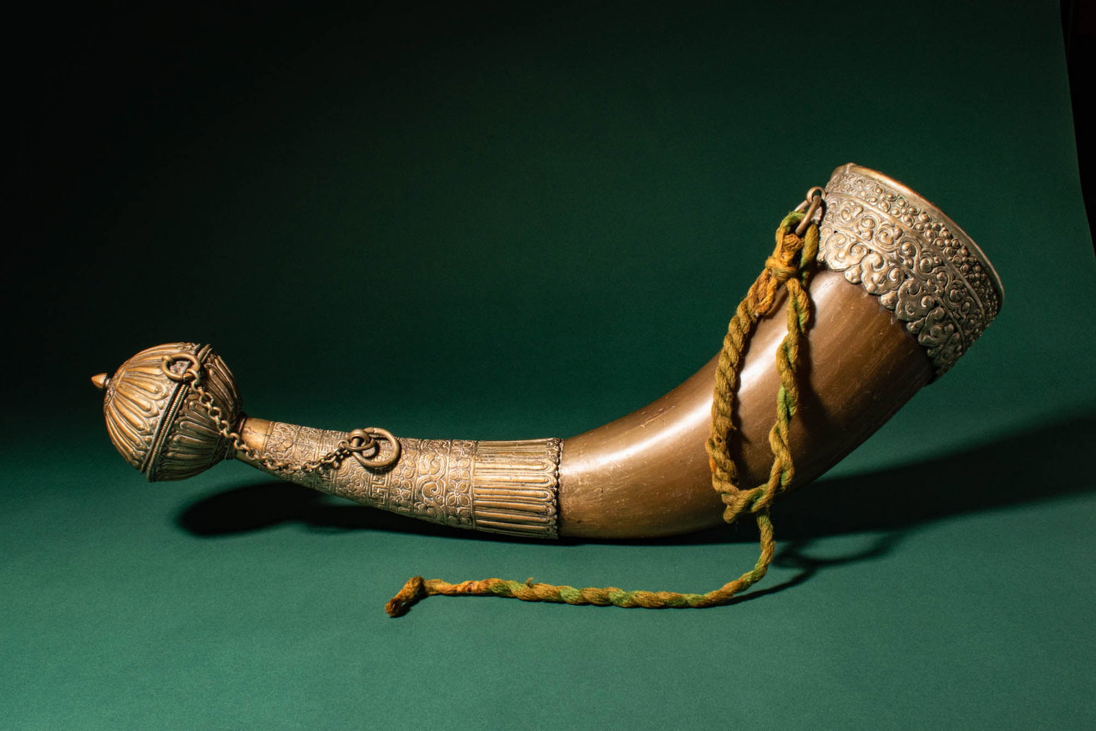 TIBETAN CHAANG DRINKING HORN: Ca. 19th century AD. >A beautiful Tibetan drinking horn (chaang horn), formed from a natural bovine bone and mounted with decorative metal fittings. The gently curving body tapers toward a narrow term
