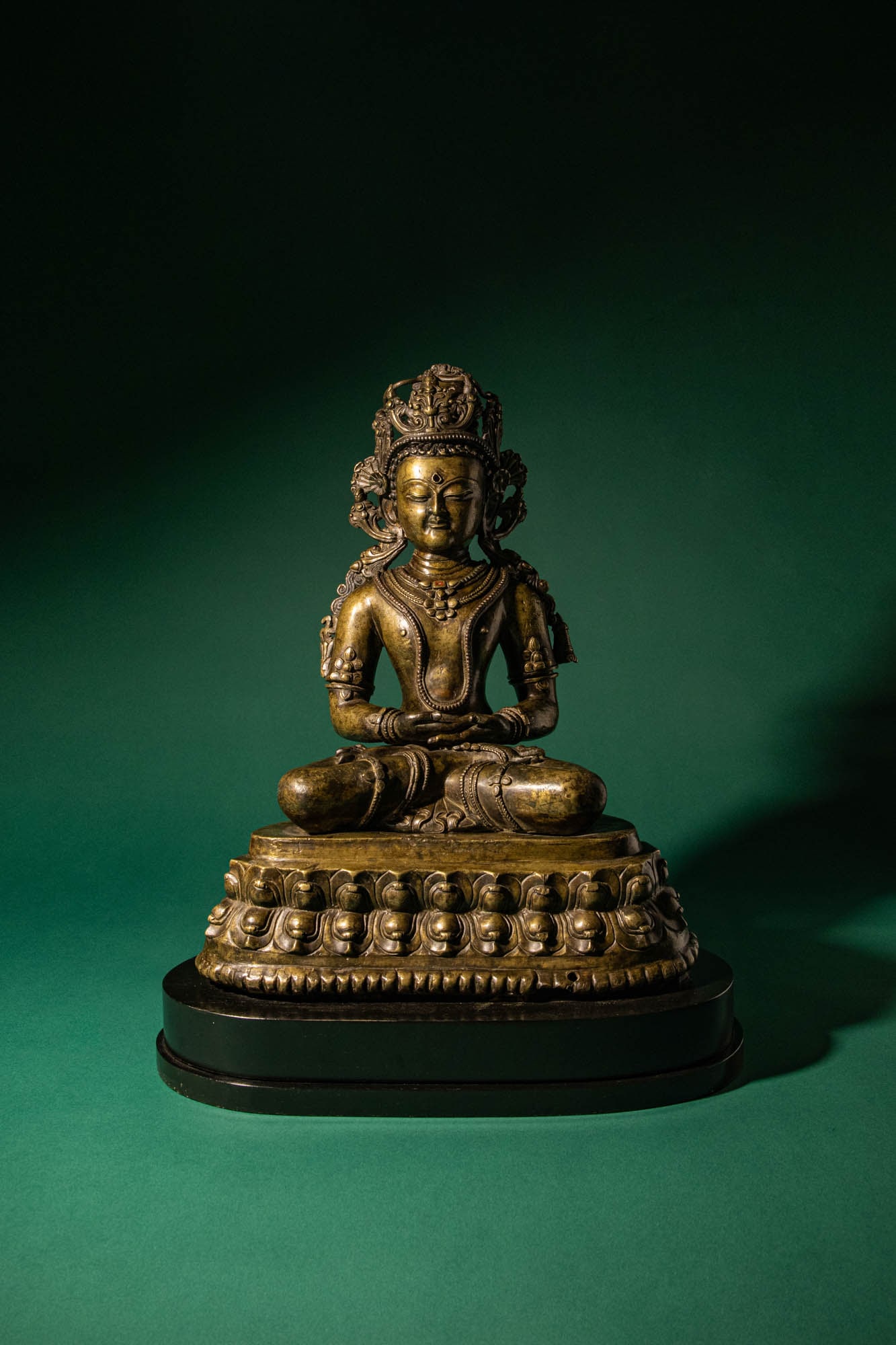 RARE CENTRAL TIBETAN SEATED FIGURE OF KUNZANG AKOR, BON DEITY: Ca. 14th century AD. > A finely cast copper alloy figure depicting Kunzang Akor, seated in serene meditation upon a well-articulated double-lotus base. The deity is shown in vajraparyankasana (full lo