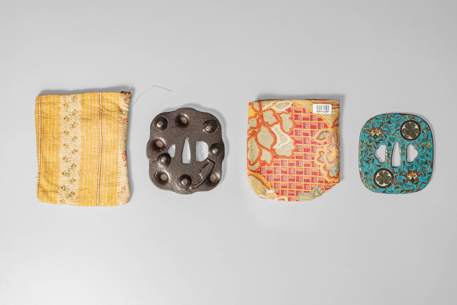 TWO JAPANESE TSUBA, SIGNED NOBUIE AND ANONYMOUS: Edo Period, Ca. 18th-19th century AD. A group of two tsuba: an iron mokko-gata tsuba with a moulded surface and raised domed bosses in relief, attributed to the Nobuie school, known for its bold simpl