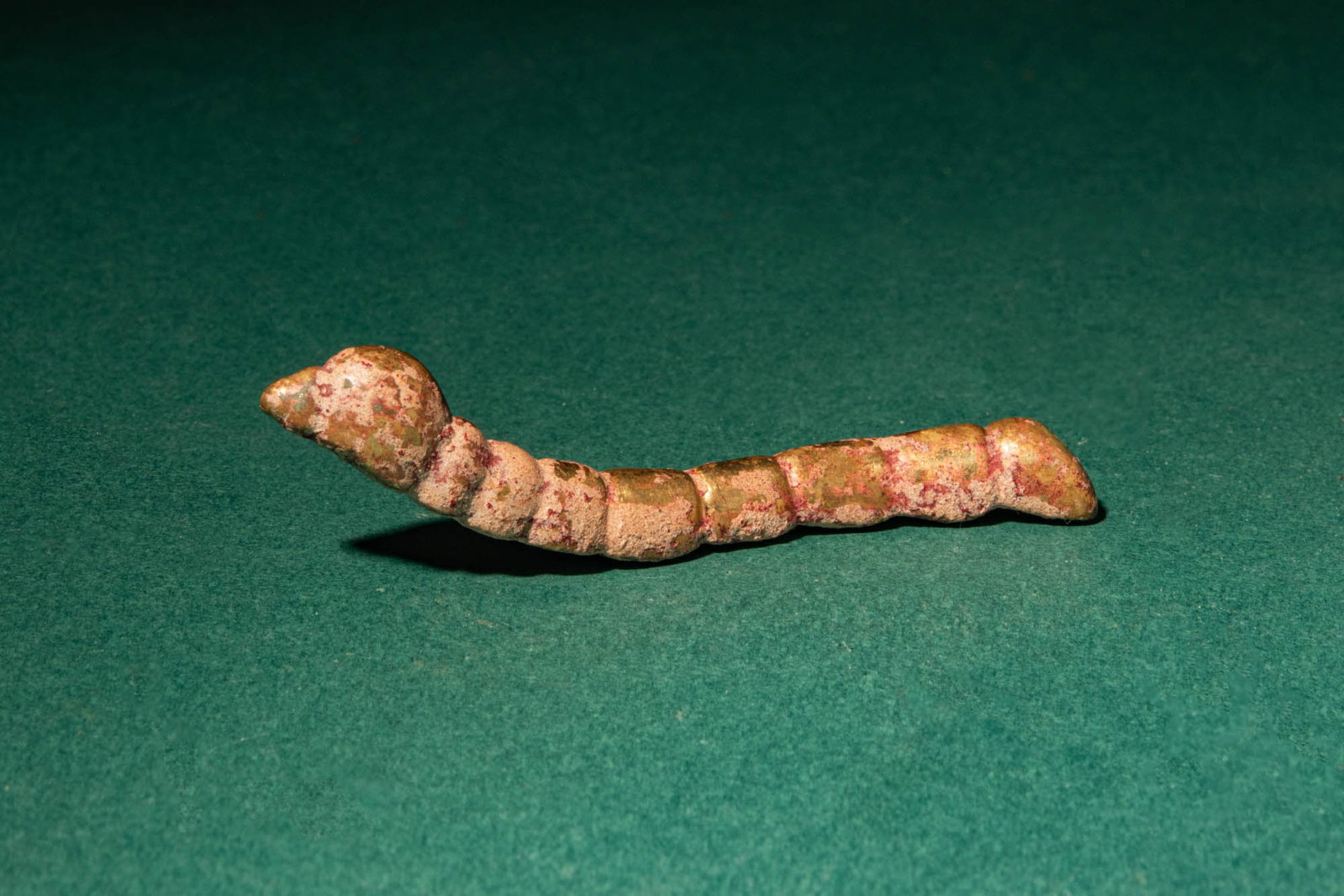 CHINESE GILDED BRONZE SILKWORM: Han Dynasty, Ca. 202 BC - AD 220, or later. >A small yet evocative cast bronze figure of a silkworm, naturalistically rendered in a gently undulating form. The segmented body is articulated through a 