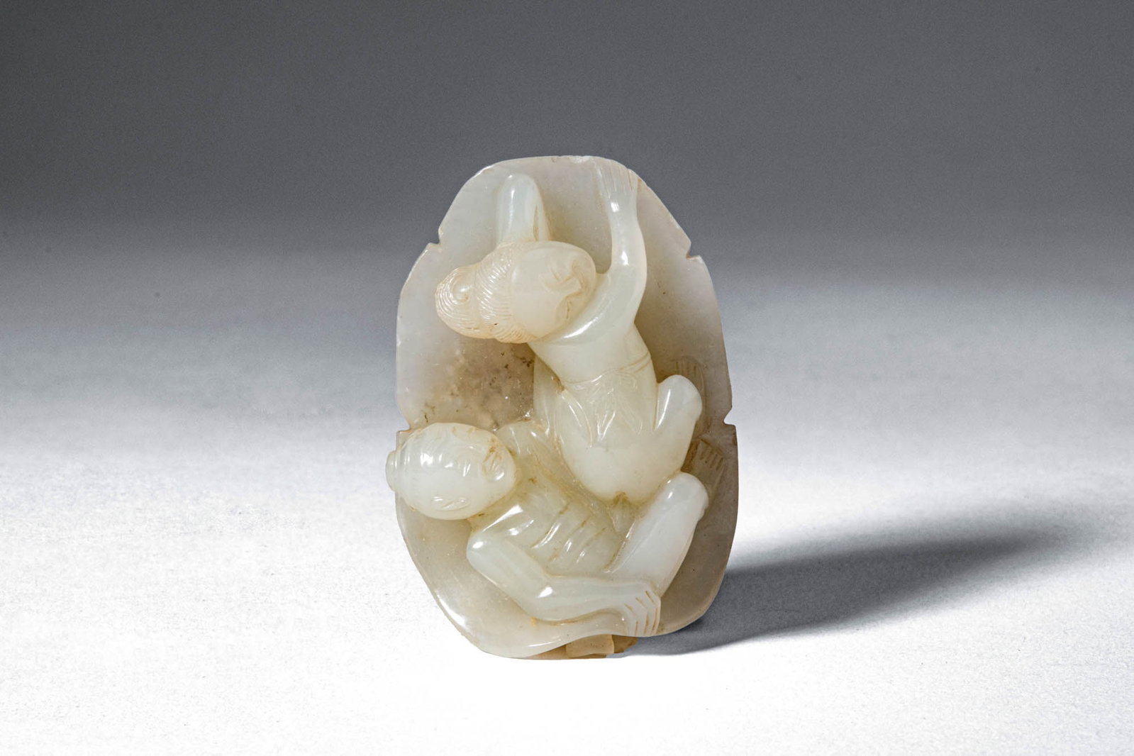 CHINESE JADE EROTIC GROUP: Qing Dynasty, Ca. AD 1644 - 1912. >A carved jade group depicting an erotic scene in a dynamic pose, rendered in the round and set against a naturalistically shaped backing. >Provenance: Private Britis