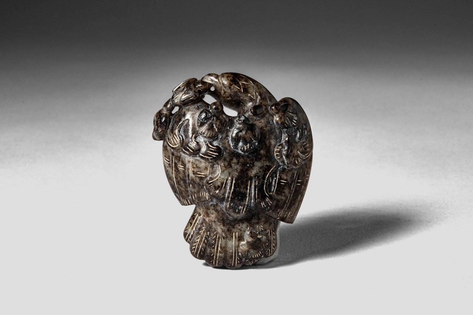 CHINESE BLACK JADE EAGLE: Ming Dynasty, Ca. AD 1368 - 1644, or earlier. >A finely carved jade figure depicting an eagle with wings partially folded, the bird rendered in a compact, sculptural form. The stone is of dark, mottle