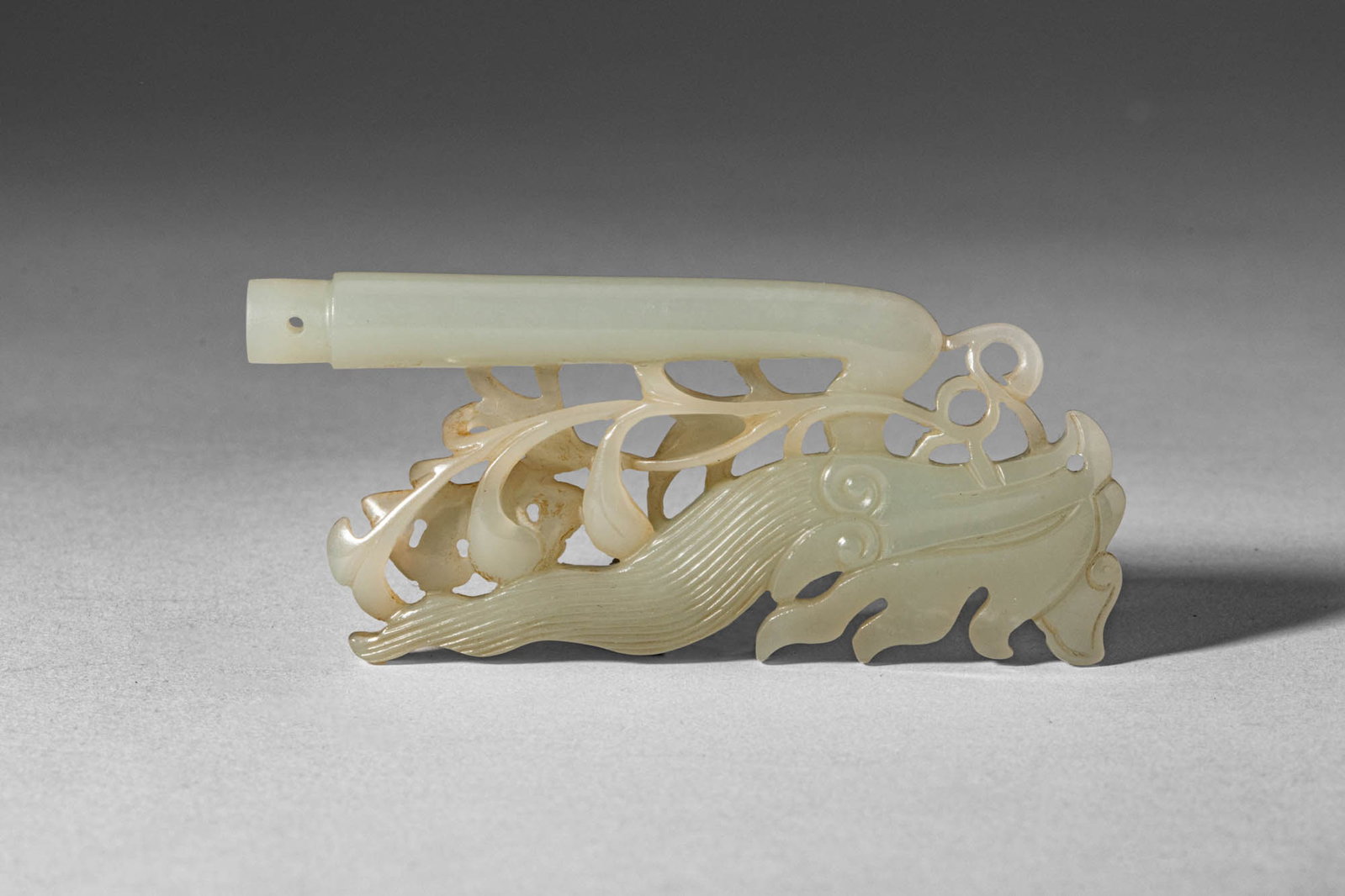 CHINESE PALE CELADON JADE PHOENIX HAIRPIN FINIAL: Ming Dynasty, Ca. AD 1368 - 1644. >A carved jade hairpin finial depicting a stylised phoenix (fenghuang) in openwork, the elegant bird shown with elongated body, finely incised plumage, and a gently c