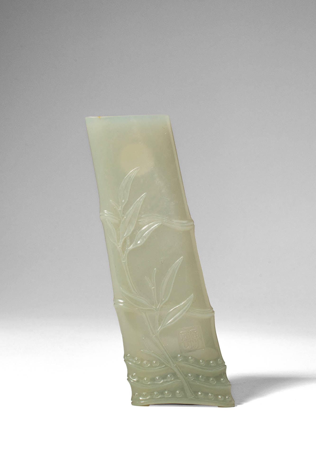 CHINESE CELADON JADE BRUSH REST CARVED IN BAMBOO FORM: Qing Dynasty, Ca. AD 1644 - 1912. >A carved celadon jade brush rest in the form of a naturalistic section of bamboo, the stone of pale green tone with soft translucency. The exterior is skilfully work