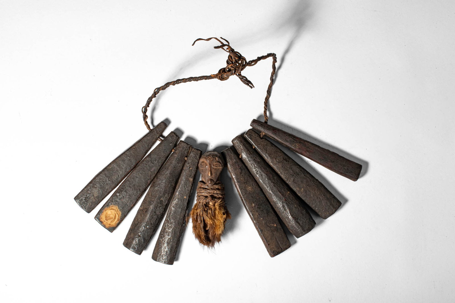 SONGYE WOODEN NECKLACE: Democratic Republic of the Congo, Ca. early 20th century AD. > A necklace comprising a strand of carved wooden elements suspended on a cord, centred by a small anthropomorphic pendant. The necklace is