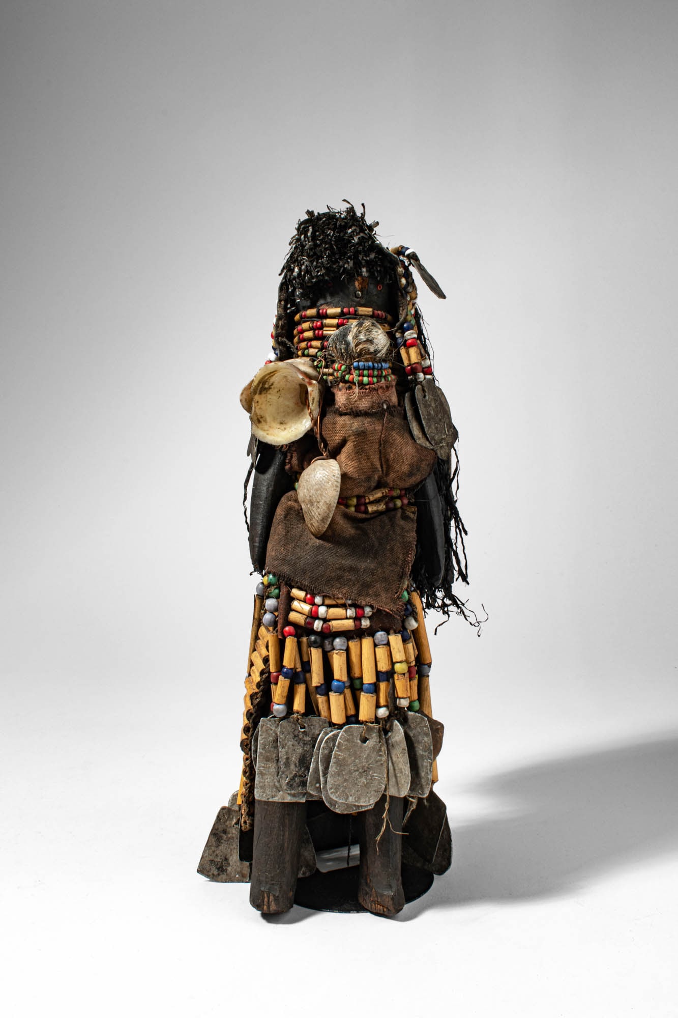 TURKANA FERTILITY DOLL, IKOKU: Ca. late 19th - early 20th century AD. >A fertility doll constructed of wood and organic materials, the figure adorned with strands of multicoloured glass beads, leather elements, fibre, and applied o