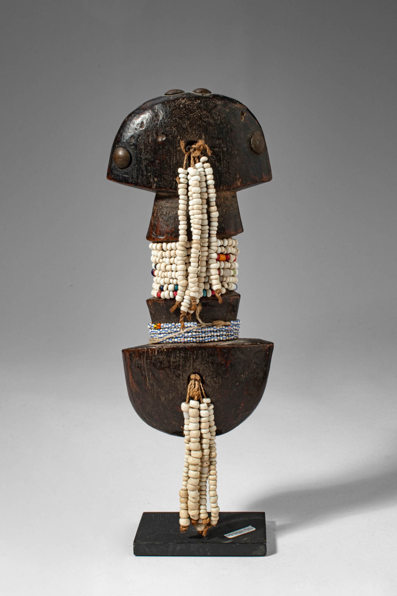 LUBA DOLL: Ca. late 19th - early 20th century AD. >A rare example of a Luba doll whose abstract, symmetrical form evokes a figure: the head punctuated with old upholstery tacks, the femininity expressed by the e