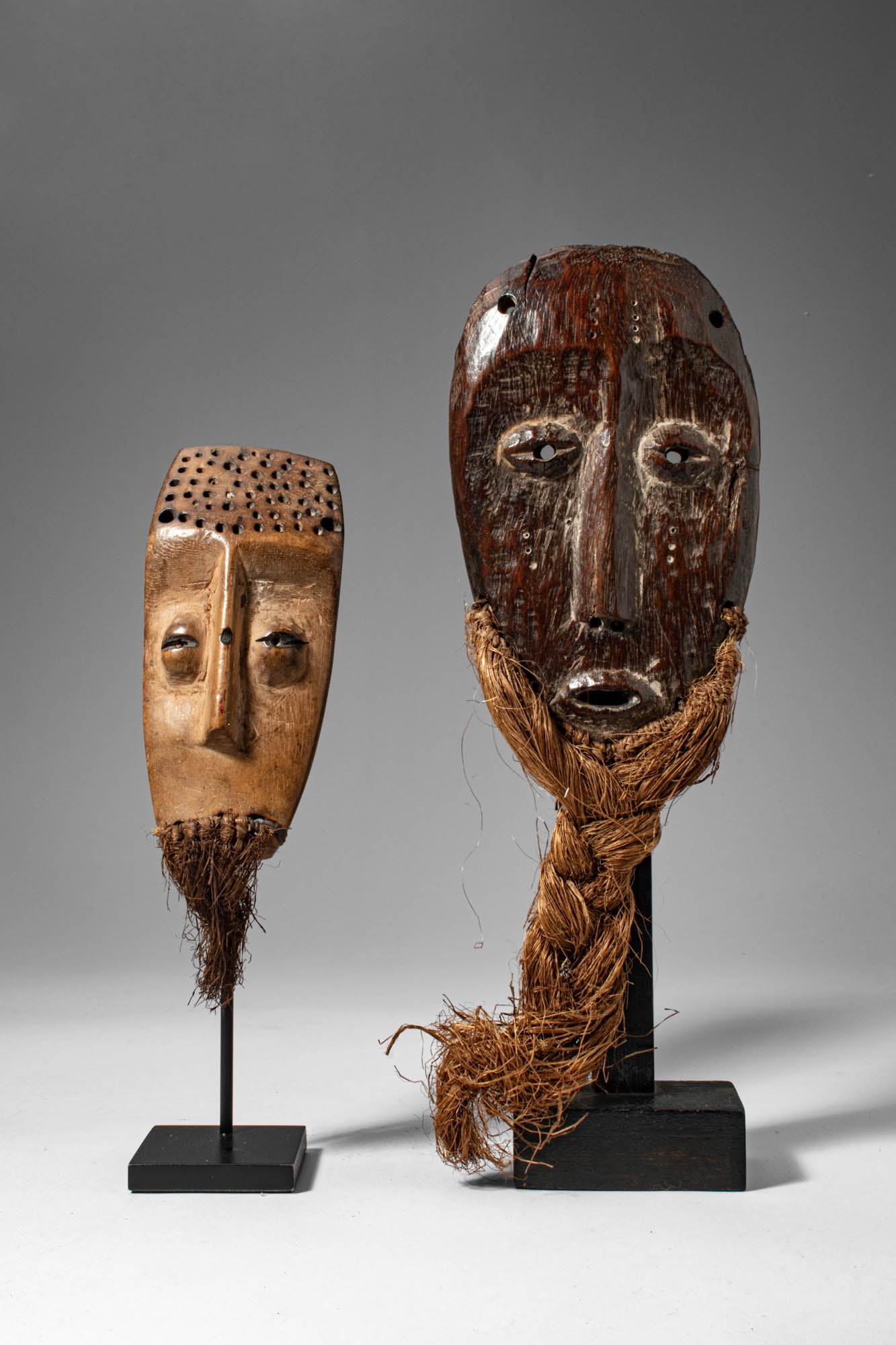 TWO LEGA MASKS: Democratic Republic of the Congo, Ca. 19th - 20th century AD. >A pair of carved wooden masks of contrasting scale and finish, both reflecting the refined minimalism characteristic of Lega artistic tra