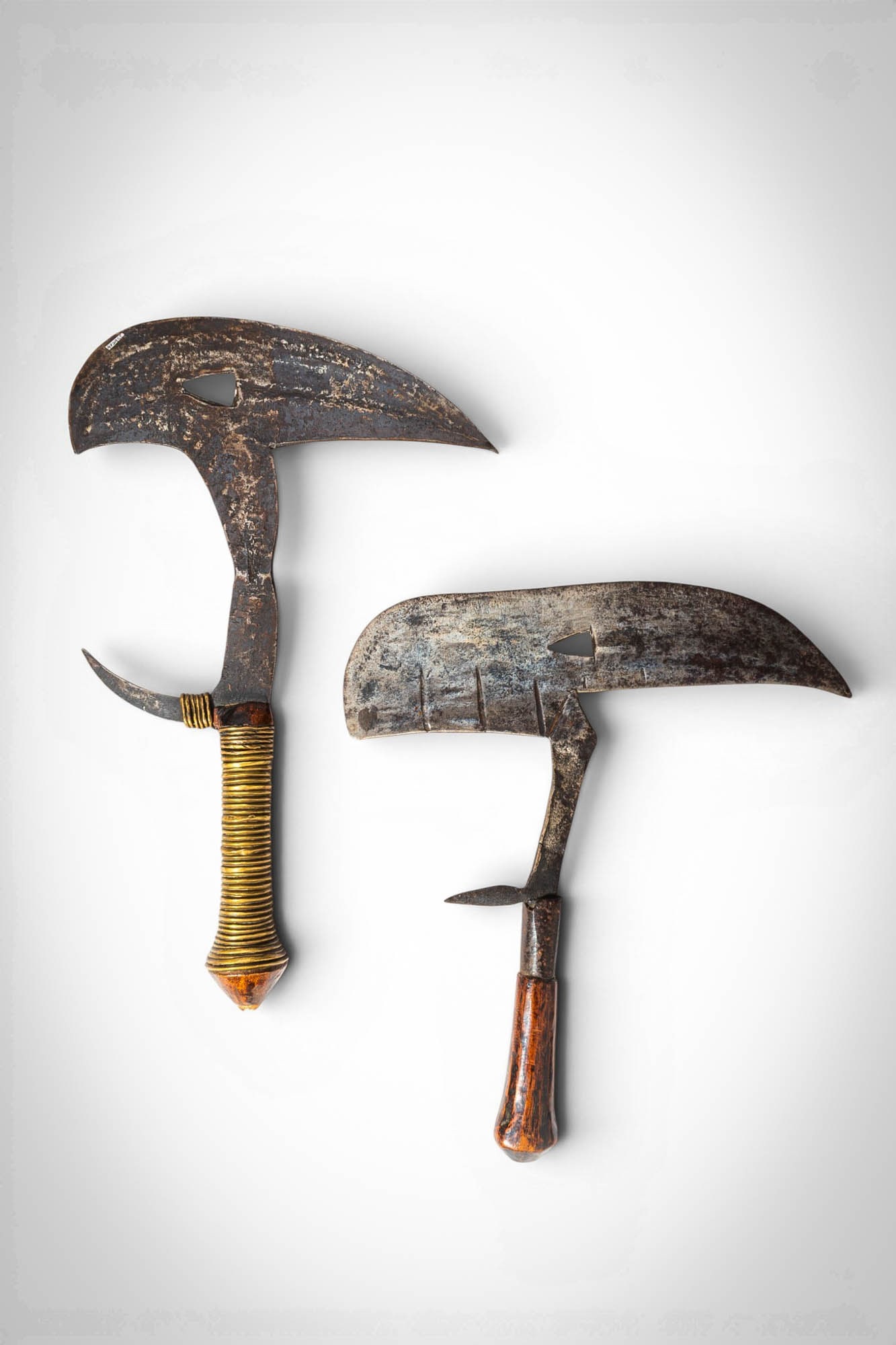 TWO THROWING KNIVES, KOTA OR FANG: Ca. 20th century AD. >A pair of iron throwing knives of characteristic curved form, attributed to the Kota or Fang peoples of Central Africa. Each features a broad, crescent-shaped blade with a forwar